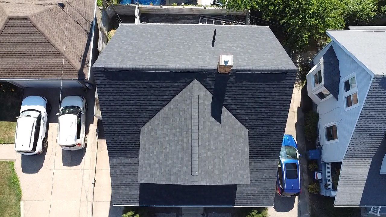 Overhead view of a house with a gray roof, chimney, and two parked cars in the driveway.