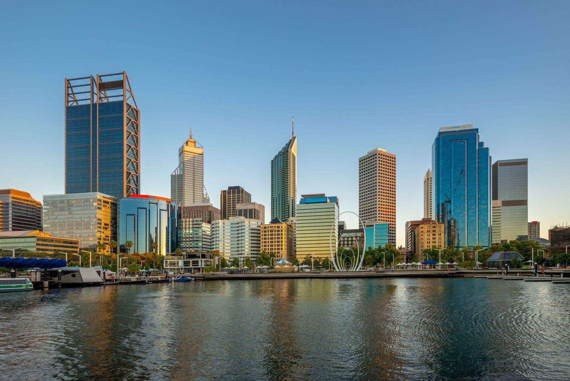 City skyline with modern skyscrapers reflected in calm water at sunset