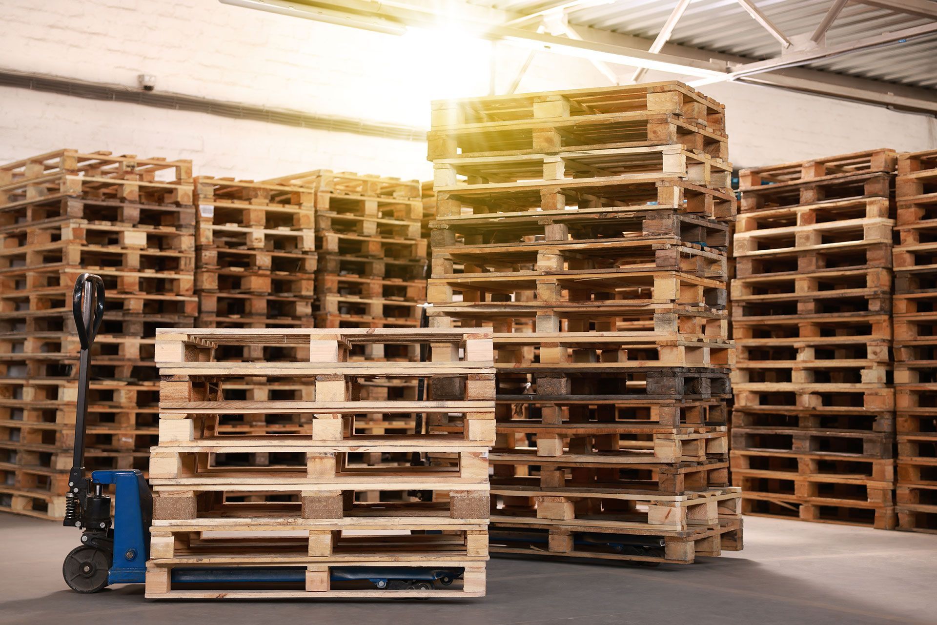 Modern manual forklift and wooden pallets in warehouse