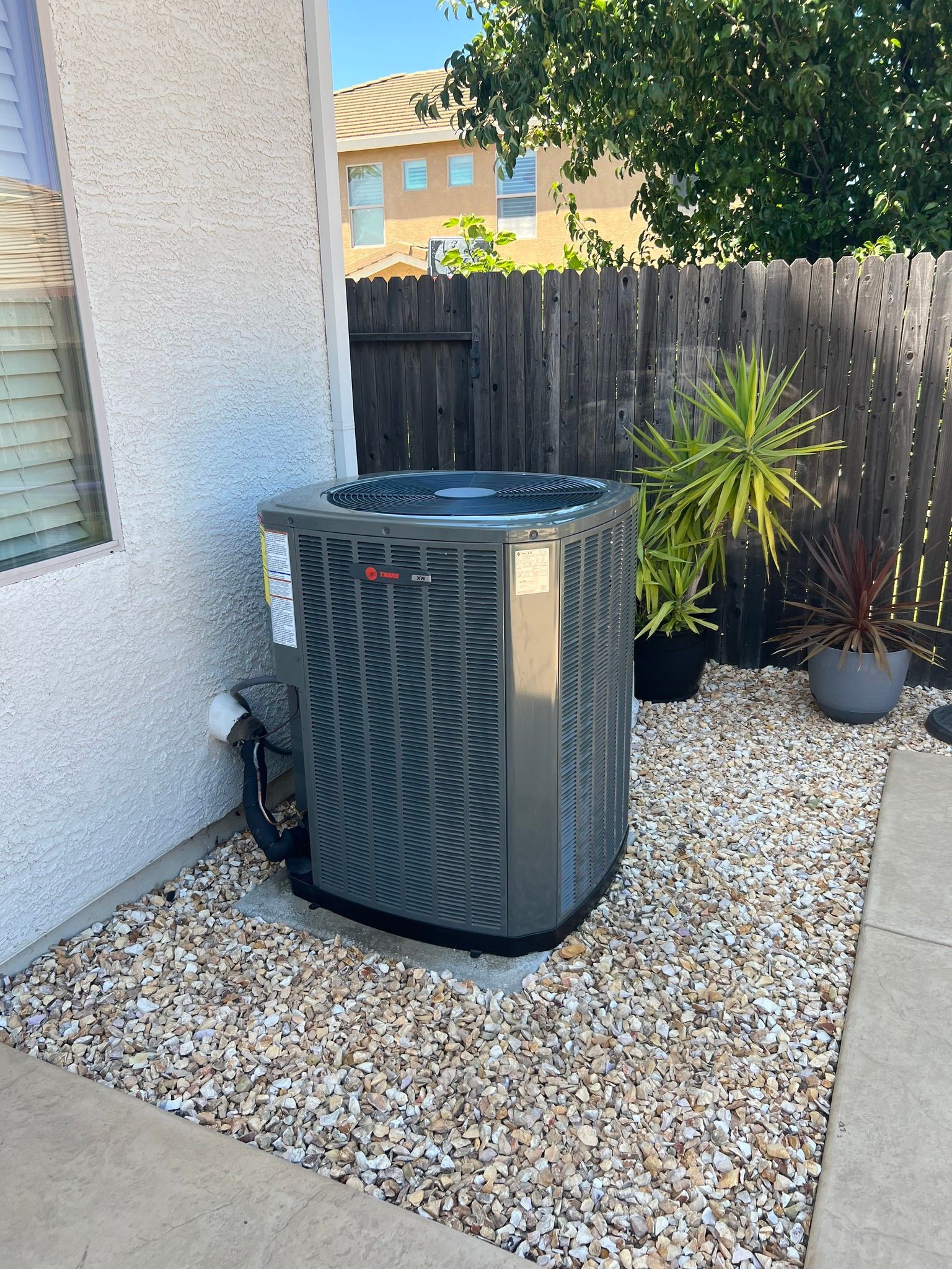 A gray air conditioner is sitting on top of a pile of gravel.