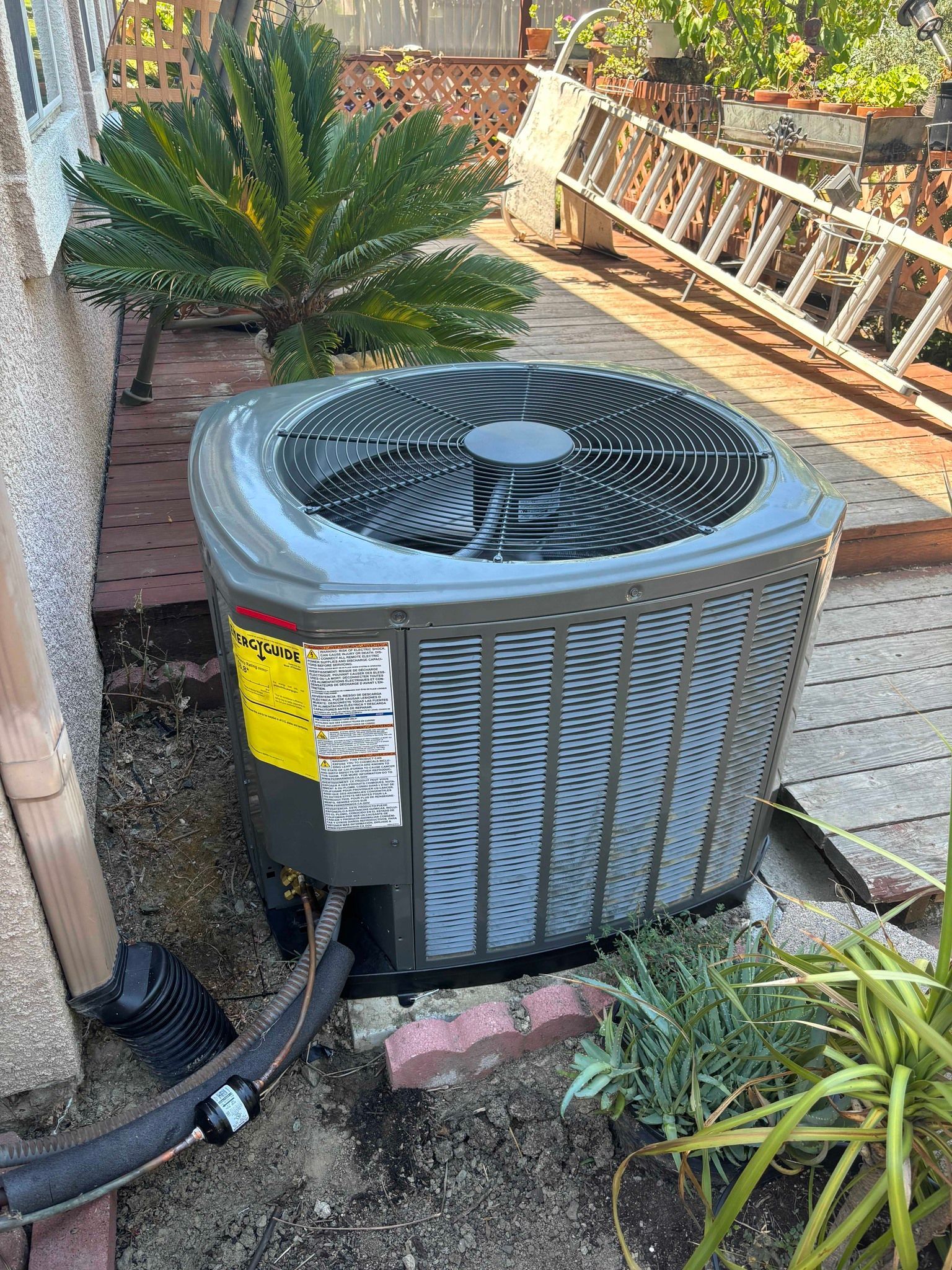 An air conditioner is sitting in the dirt next to a ladder.