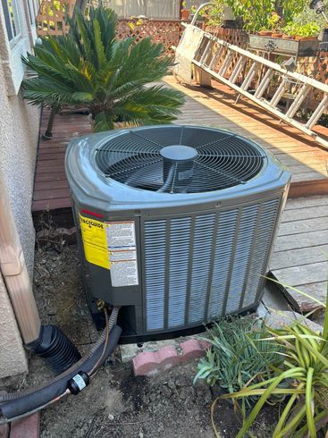 An air conditioner is sitting in the dirt next to a ladder.