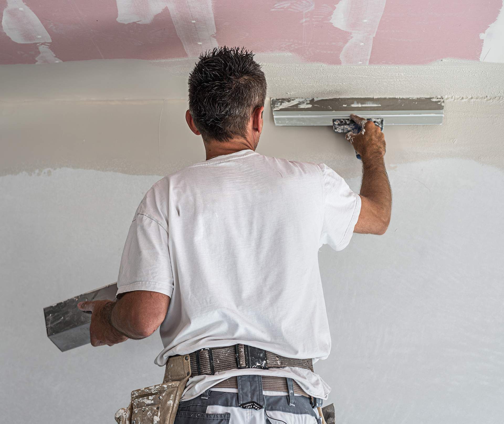 A man is plastering a wall with a spatula.