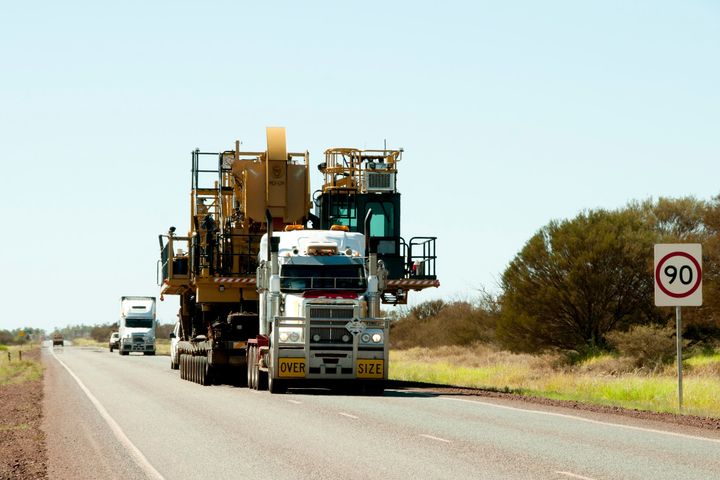 Large White Truck Carrying Heavy Machinery — Transport Services in Walkerston, QLD