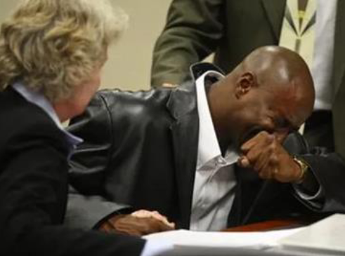 A man in a leather jacket is sitting at a table with his eyes closed.