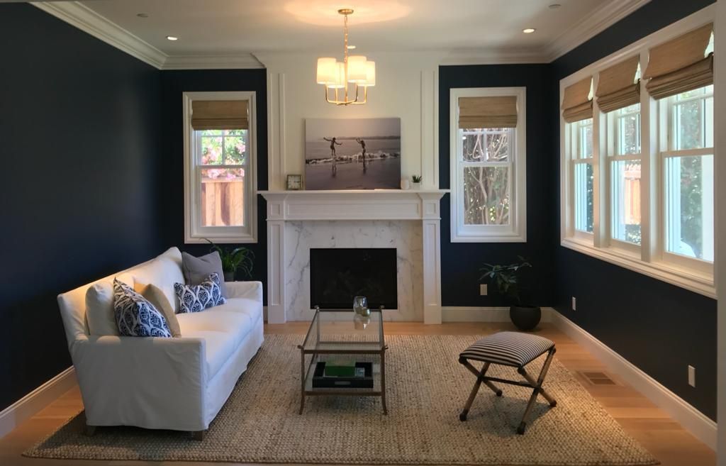 Living room with navy blue walls, white trim, fireplace, white sofa, and a glass coffee table.