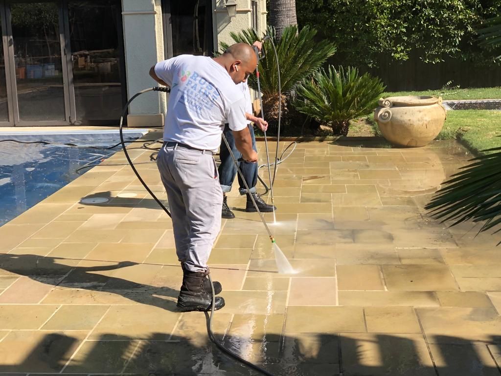 A man is cleaning a patio with a pressure washer.