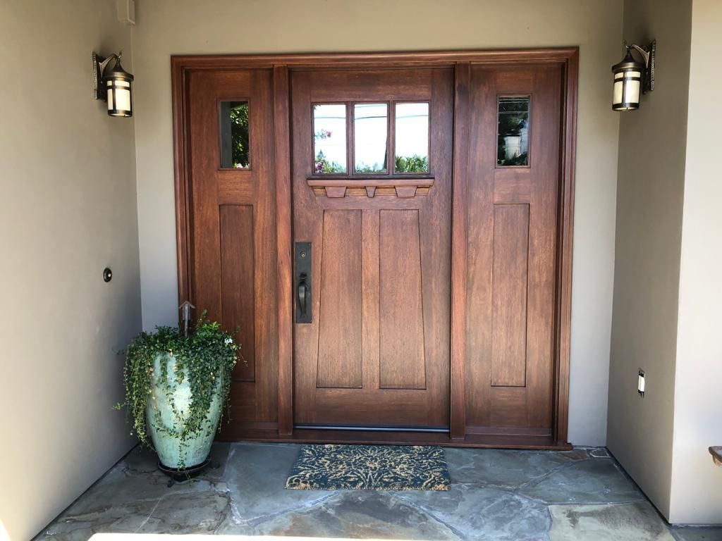A large wooden door with a potted plant in front of it.
