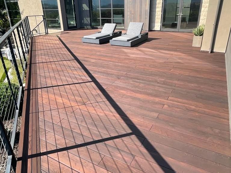 A wooden deck with chairs on it in front of a large building.