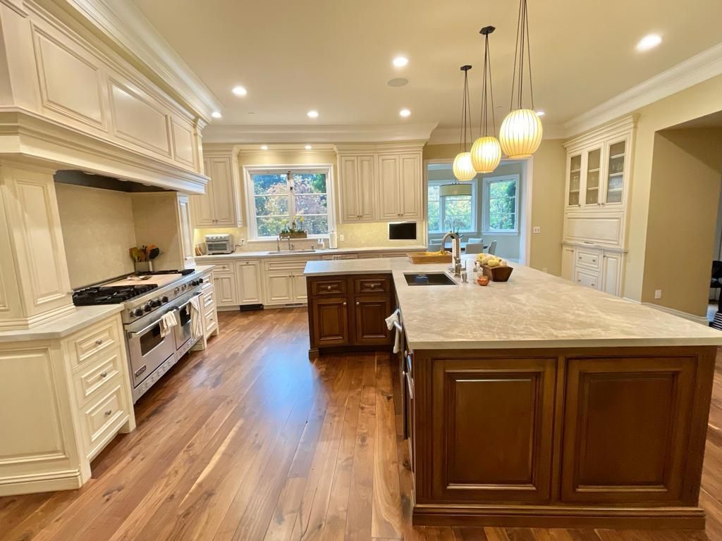 Elegant kitchen with a large island, stainless steel appliances, and wood flooring.
