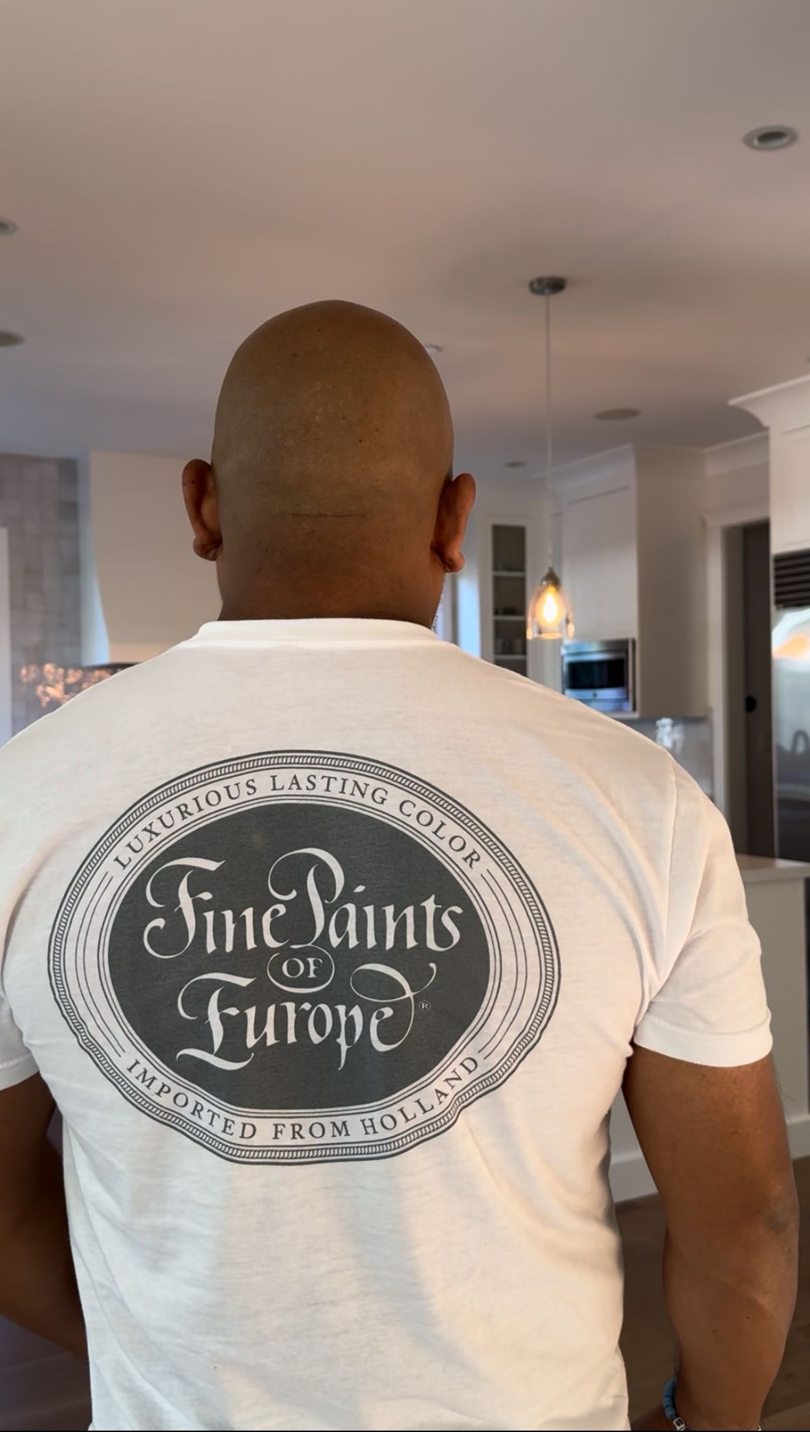 Person with a shaved head and a white t-shirt with 