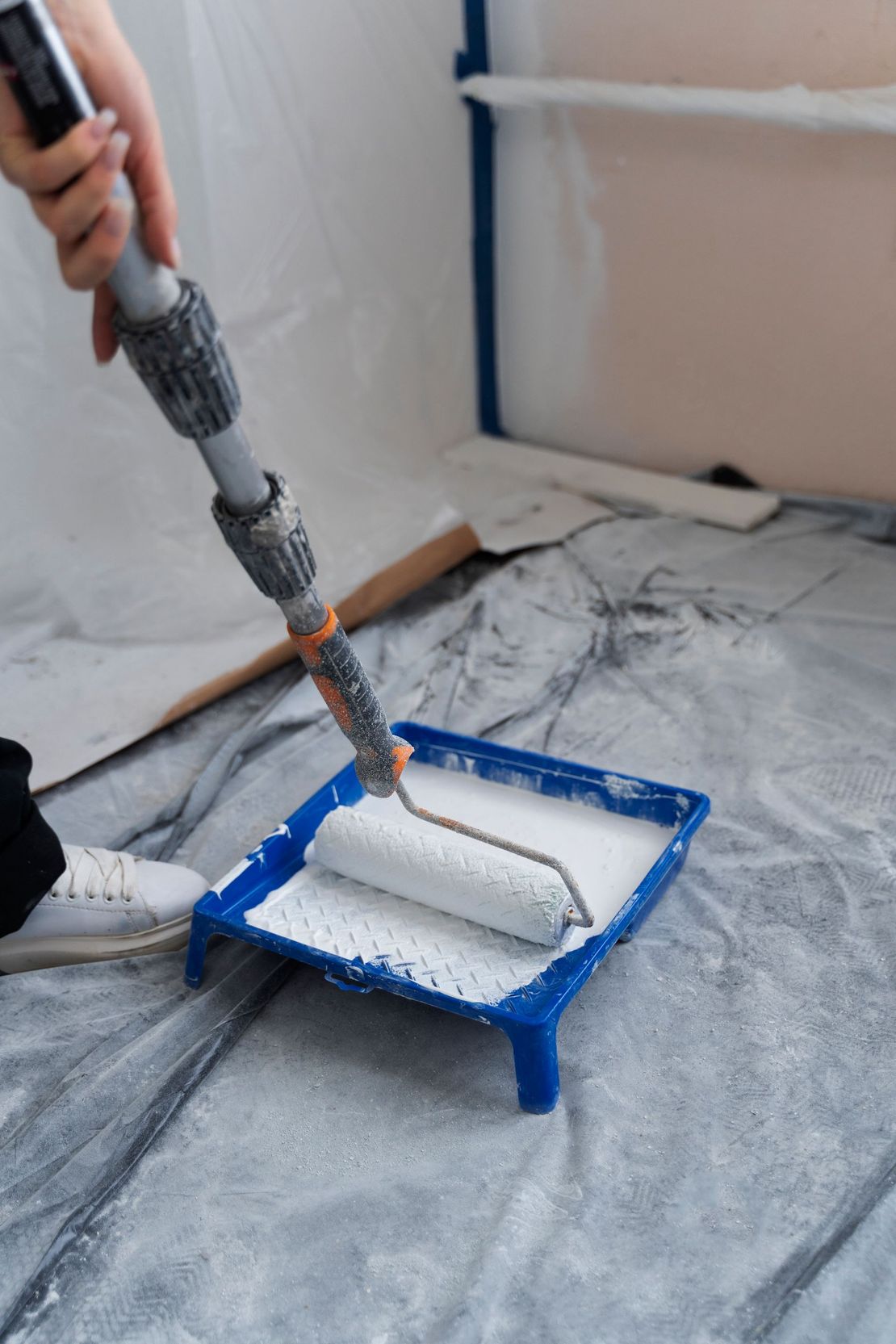 A person is painting a wall with a paint roller.