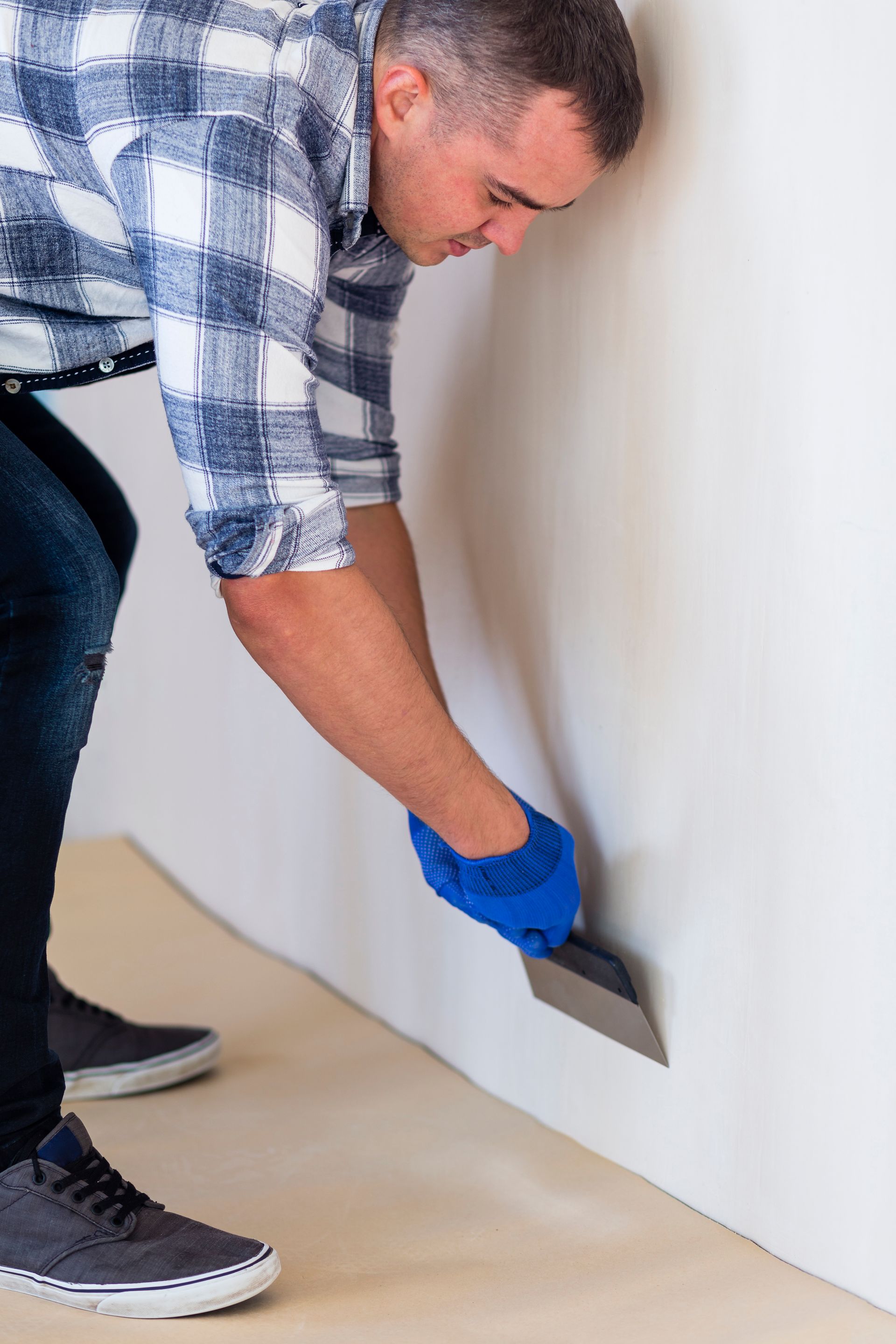 A man is applying wallpaper to a wall with a spatula.