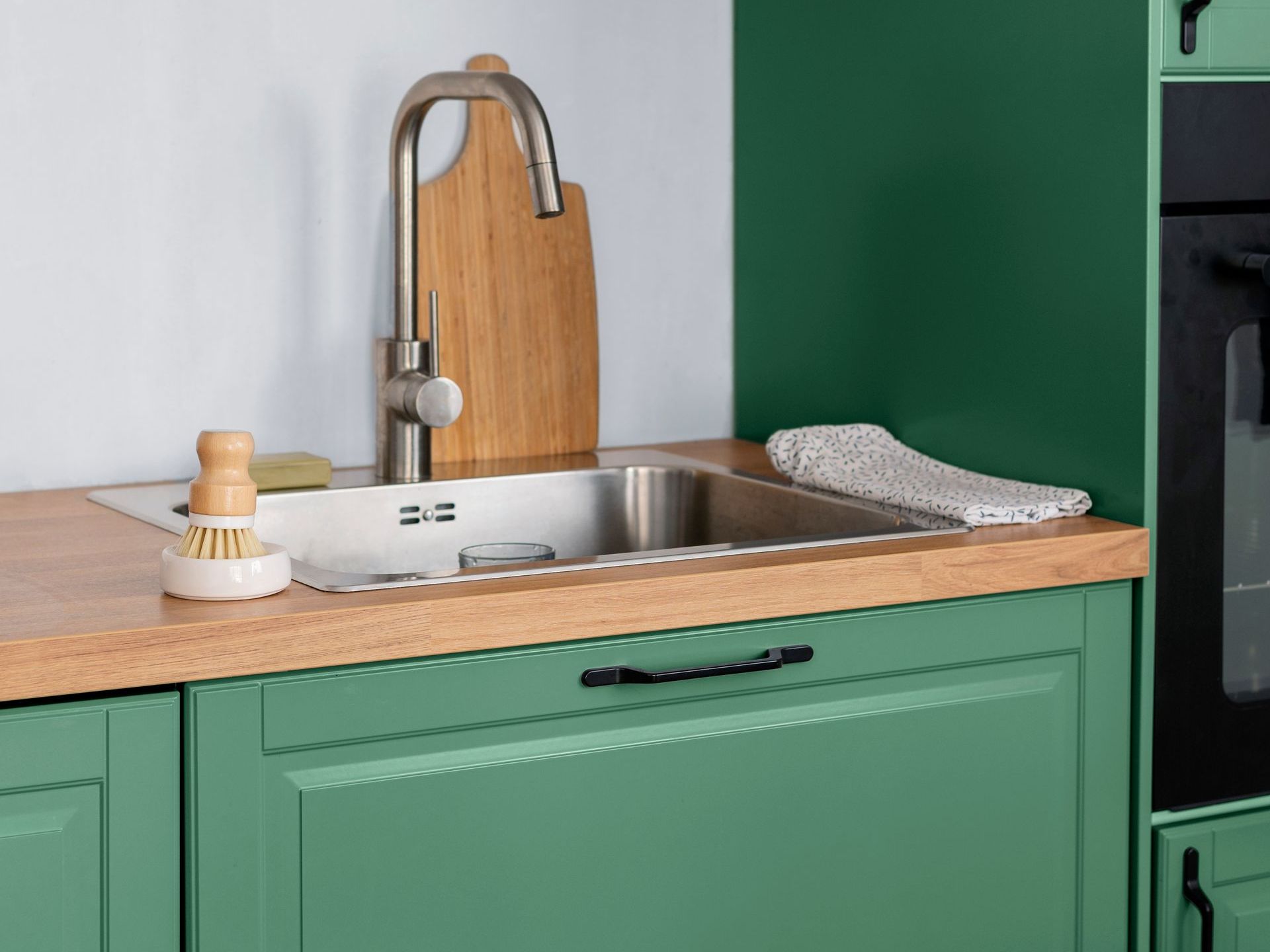 A kitchen with green cabinets and a sink.
