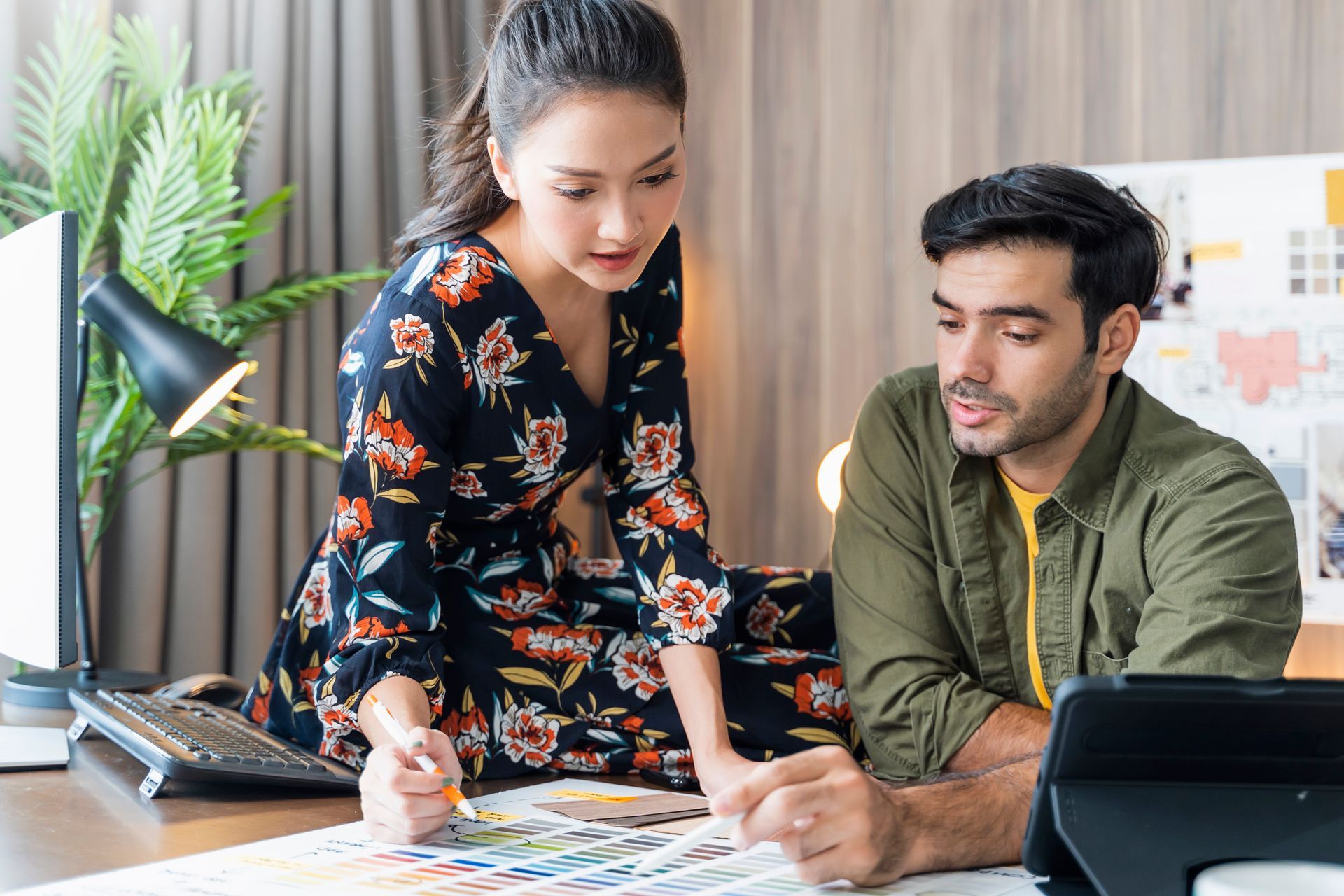 A man and a woman are sitting at a table looking at a tablet.