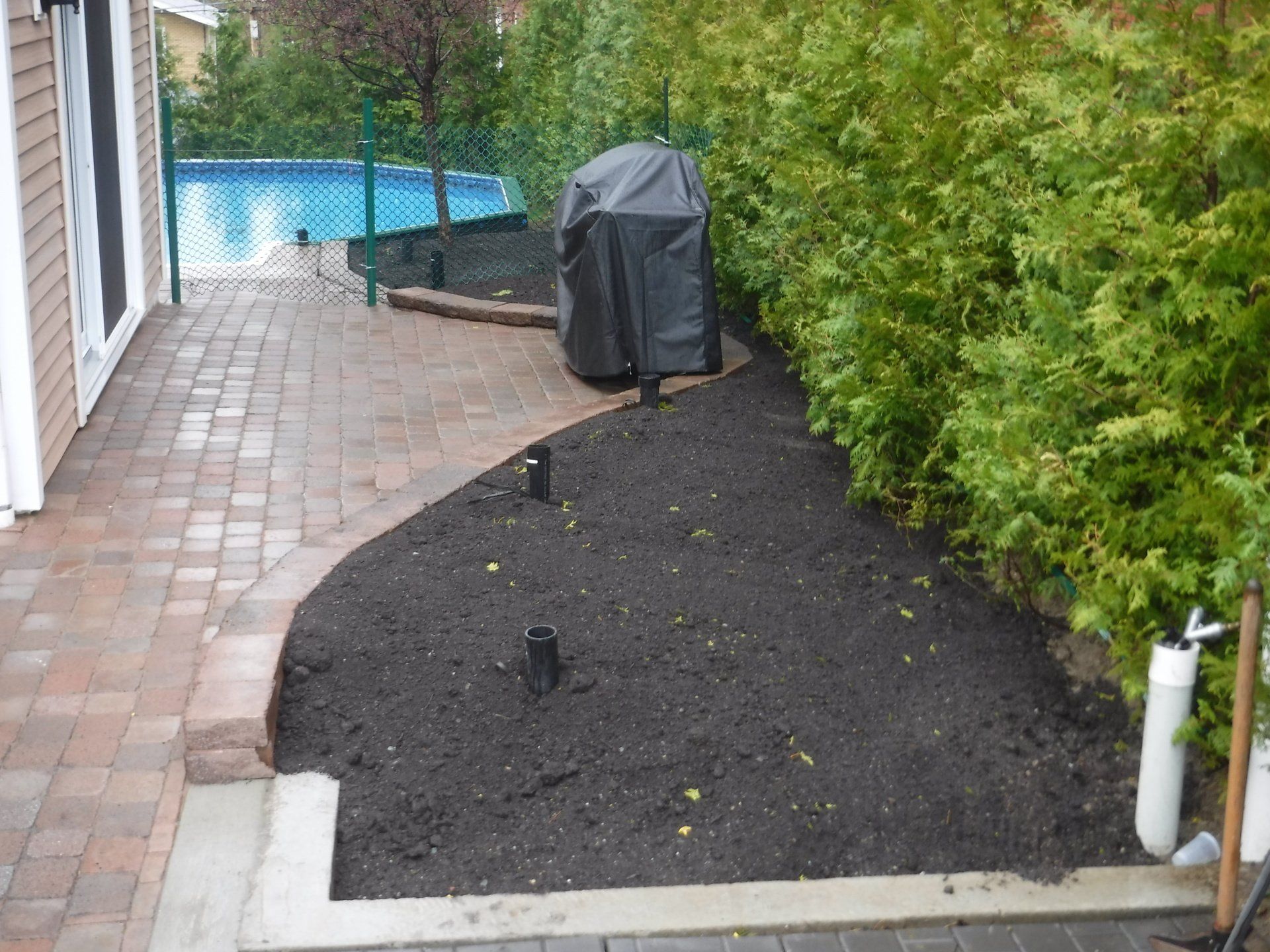 Un patio avec un grill et une piscine en arrière-plan