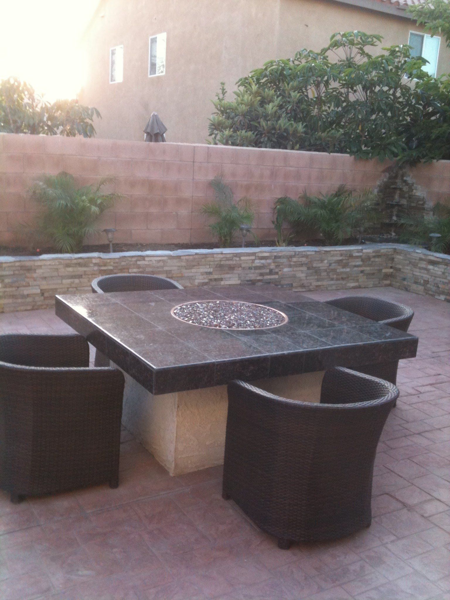 A table and chairs on a patio in front of a brick wall