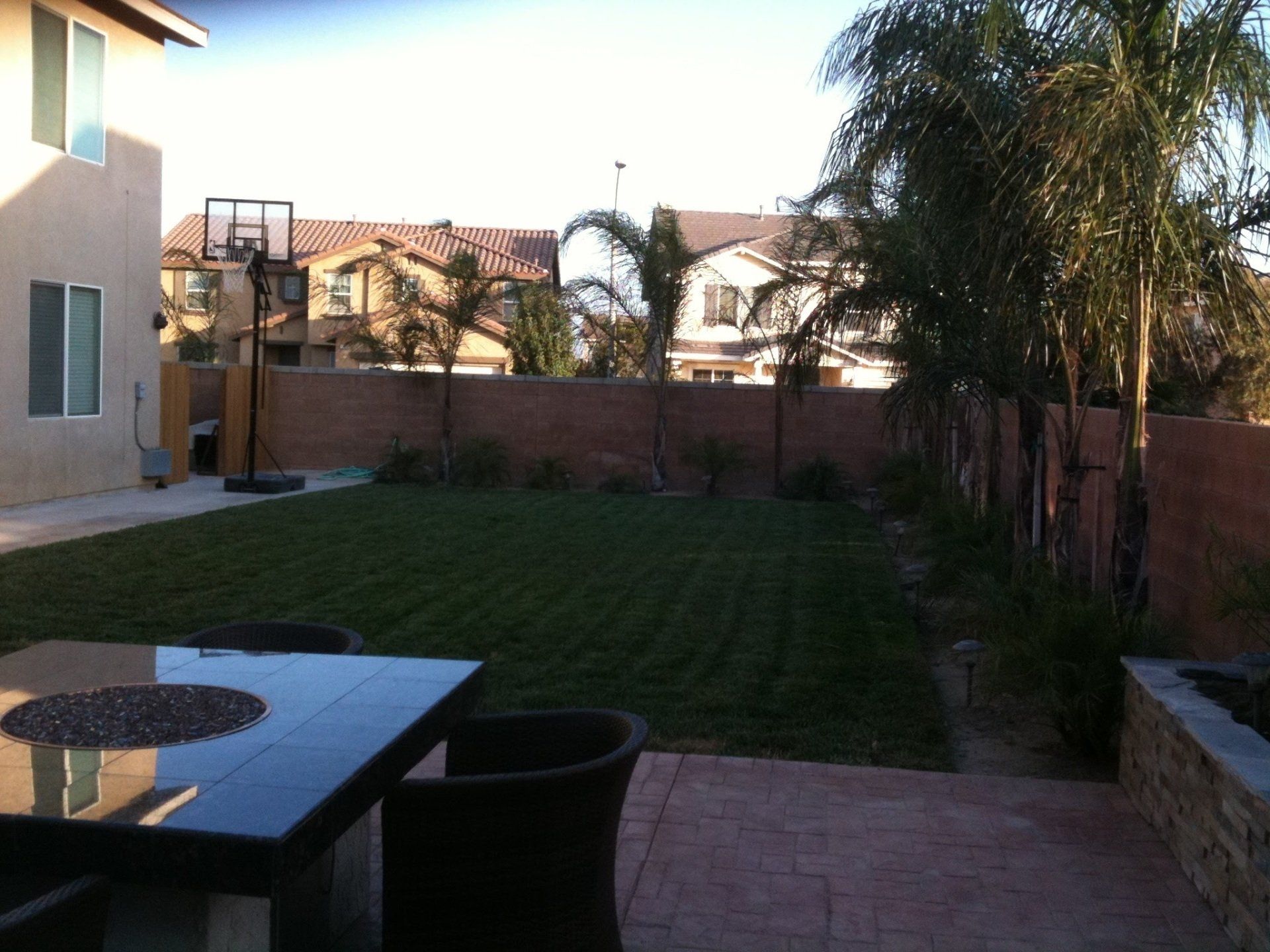 A backyard with a table and chairs and a basketball hoop