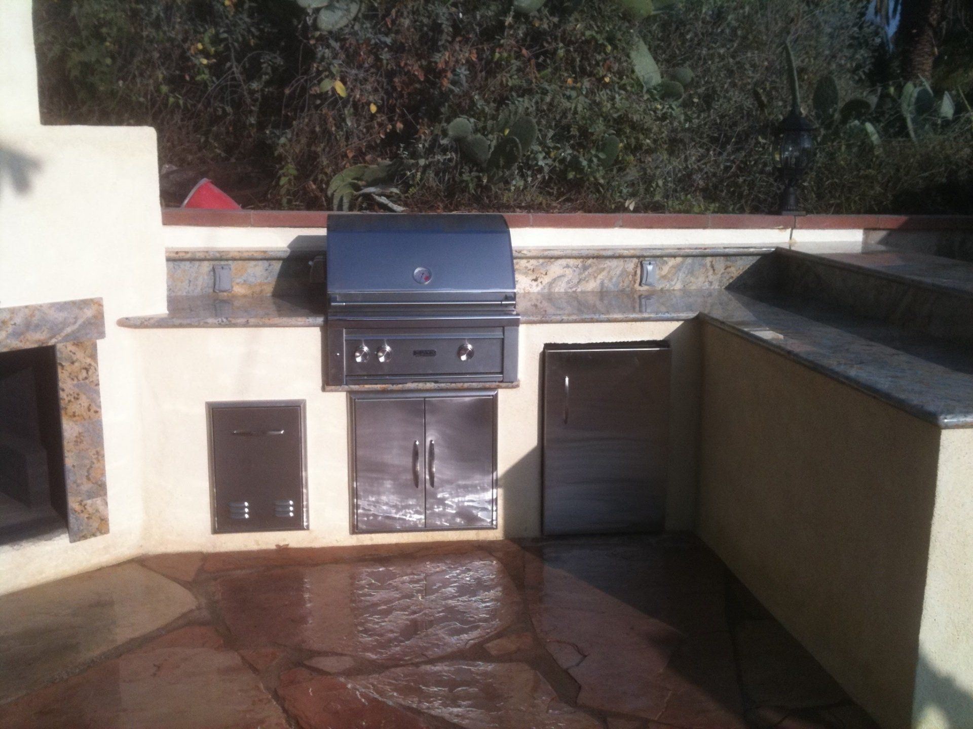 An outdoor kitchen with a grill and a fireplace