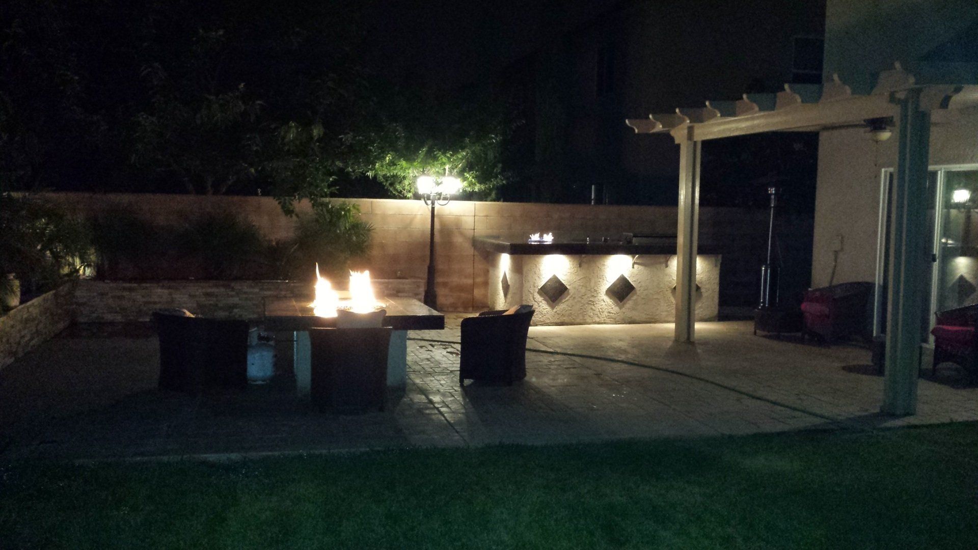 A fire pit is lit up at night in a backyard