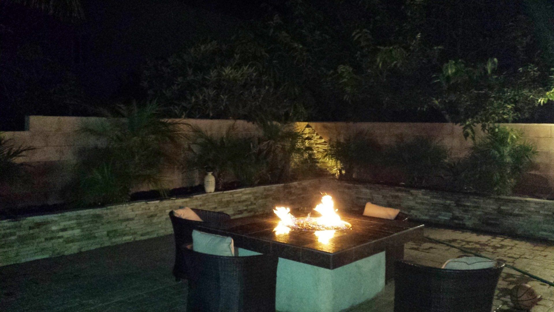 A fire pit is lit up in a backyard at night
