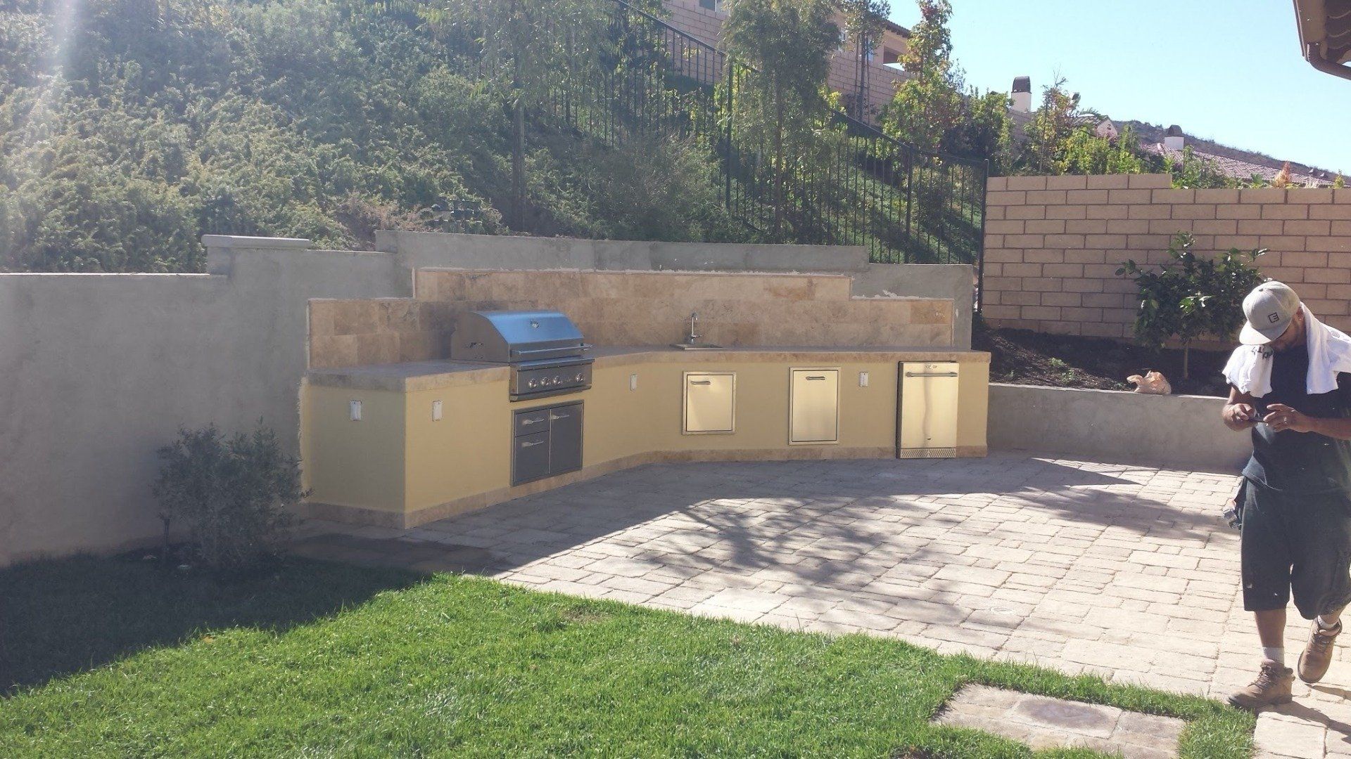 A man is standing in a backyard with a towel on his head.