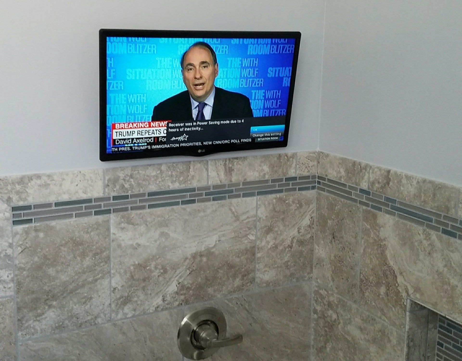 A tv in a bathroom shows a news report