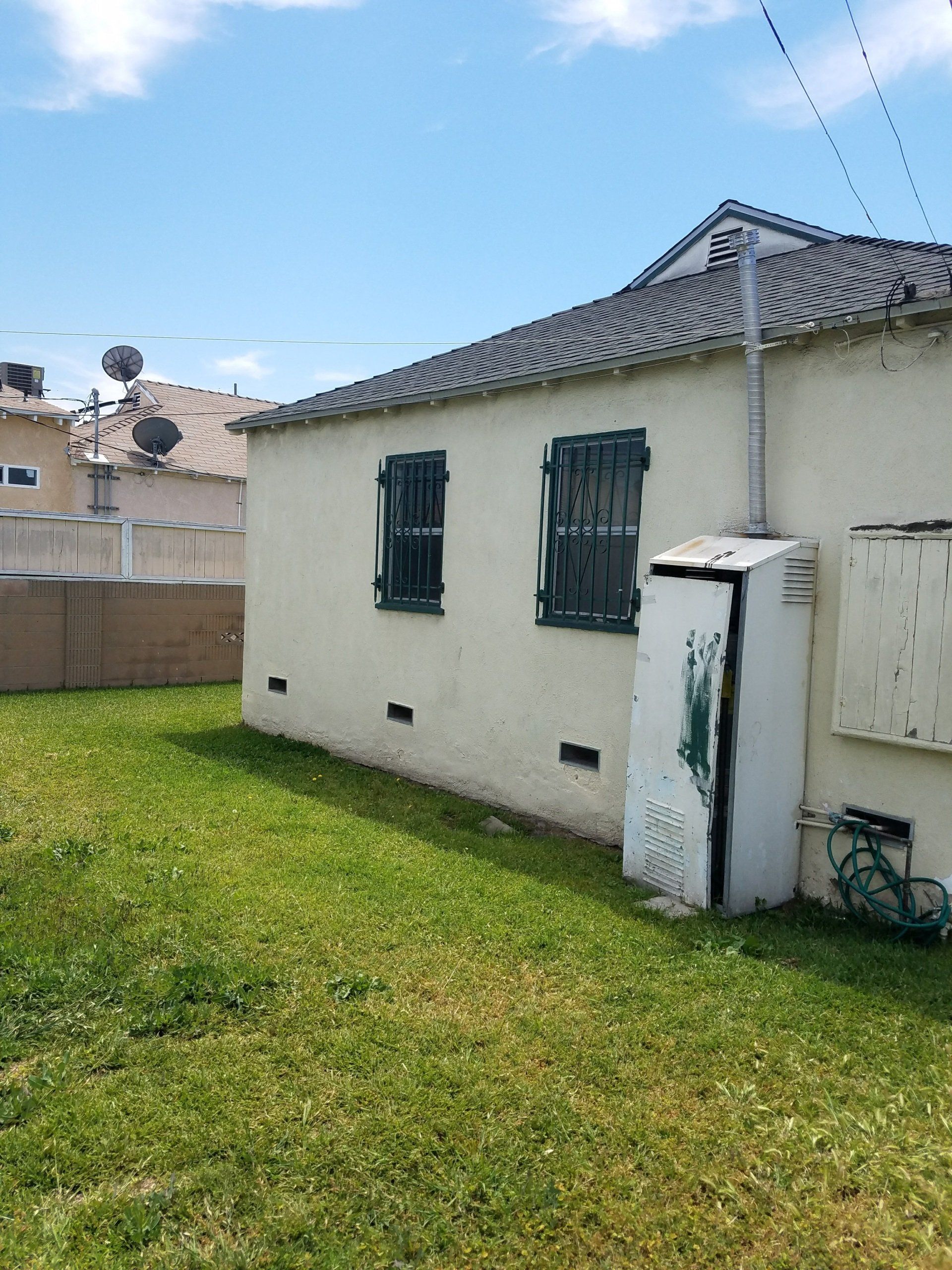 A white house with green windows is sitting on top of a lush green lawn.