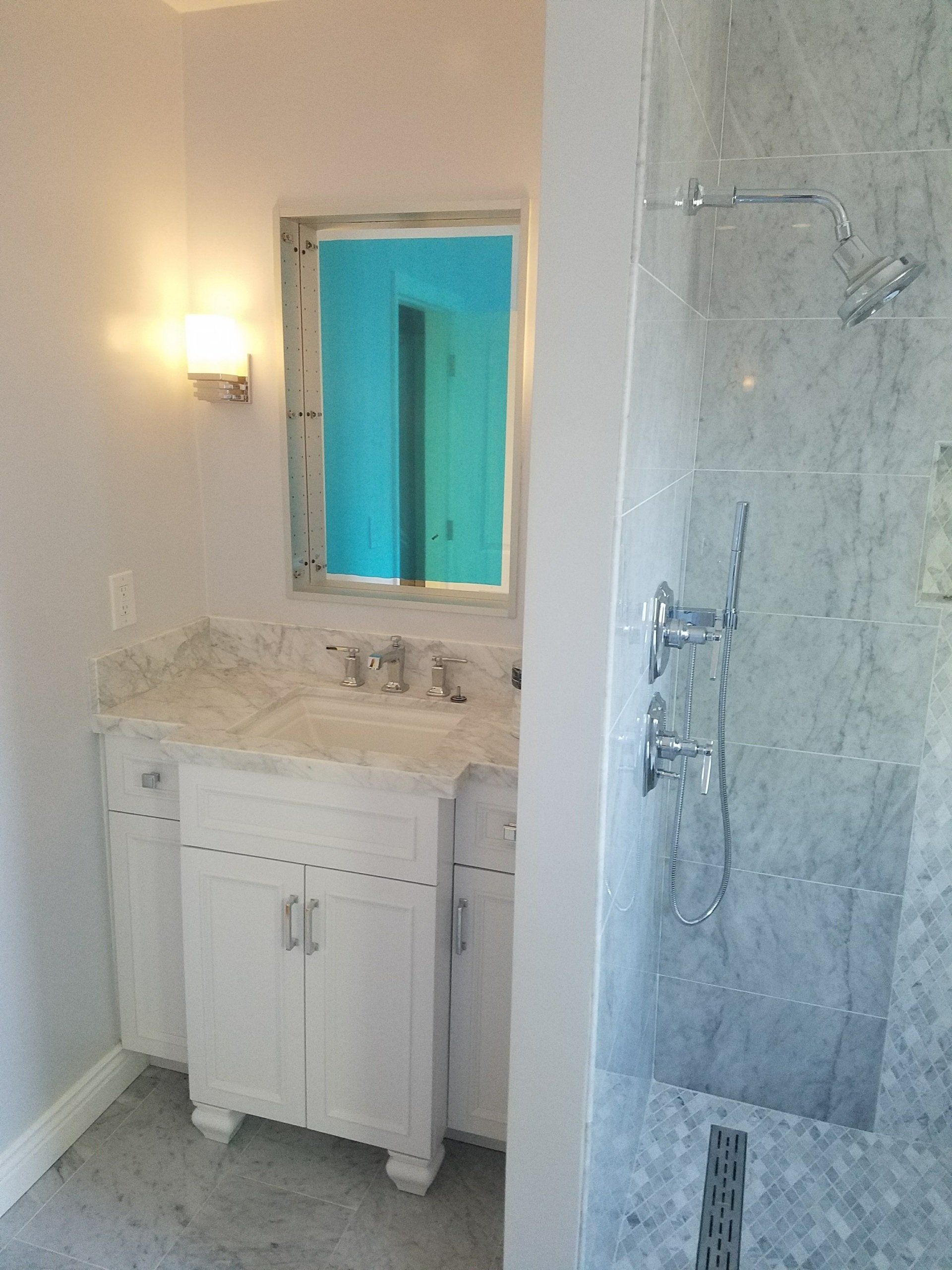 A bathroom with a sink a mirror and a shower