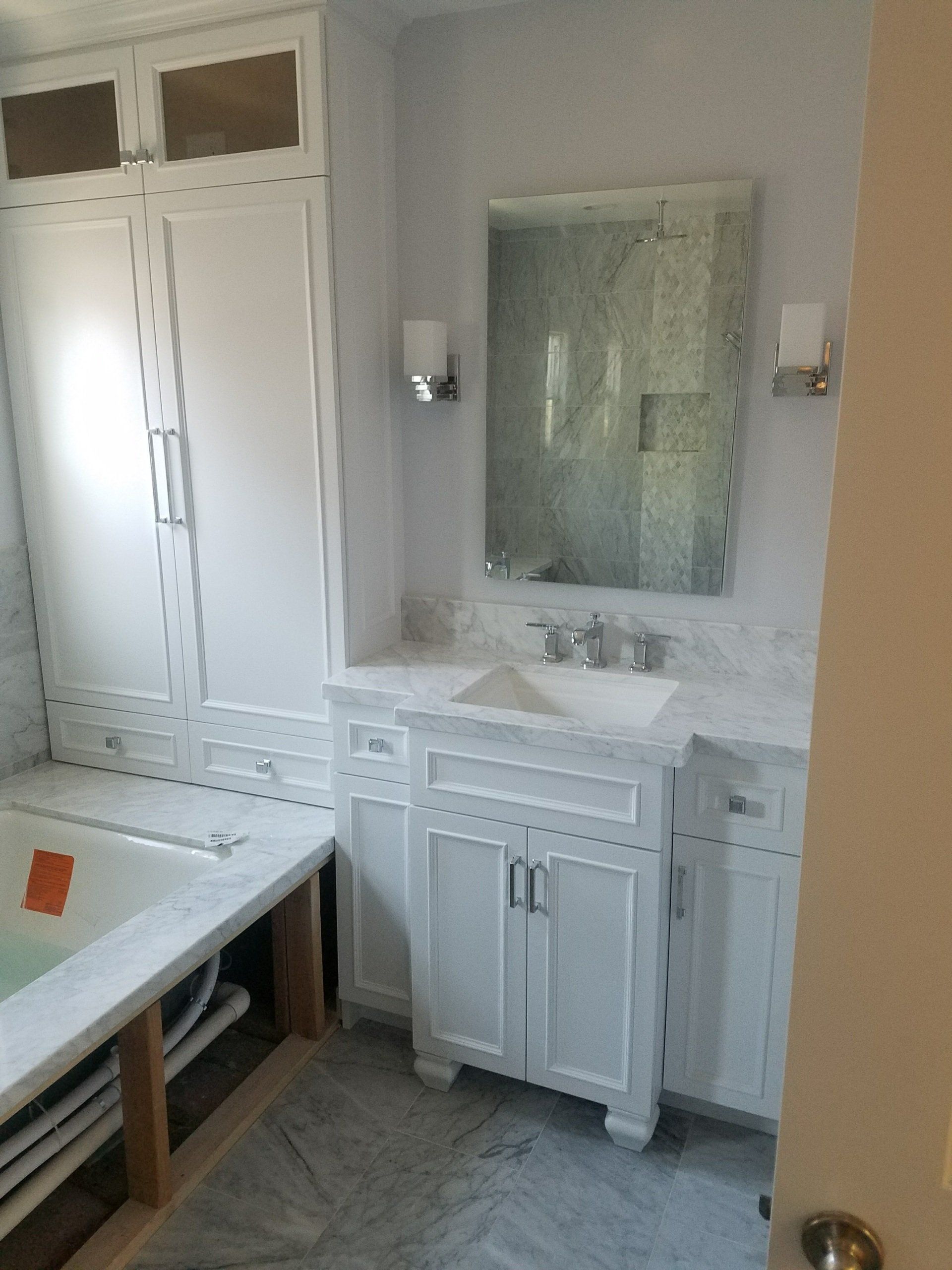 A bathroom with white cabinets , a sink , and a bathtub.