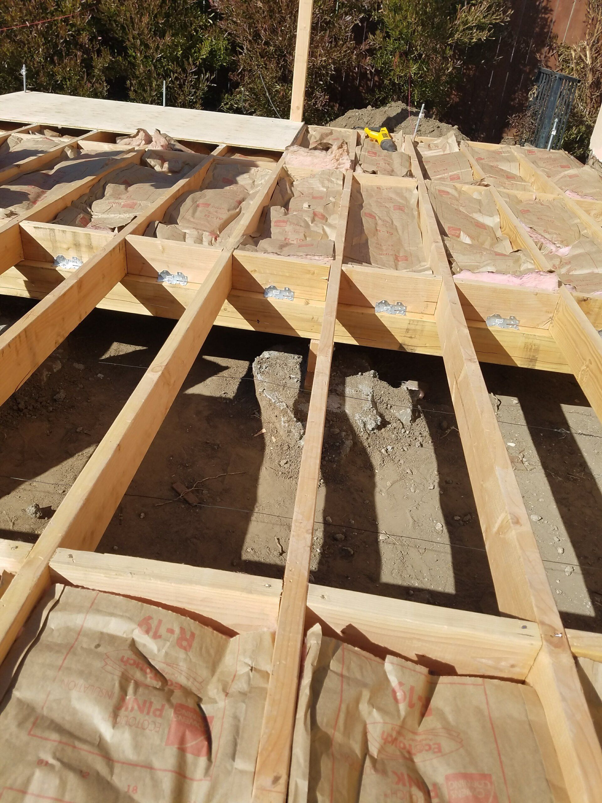 A wooden structure is being built on top of a dirt ground.