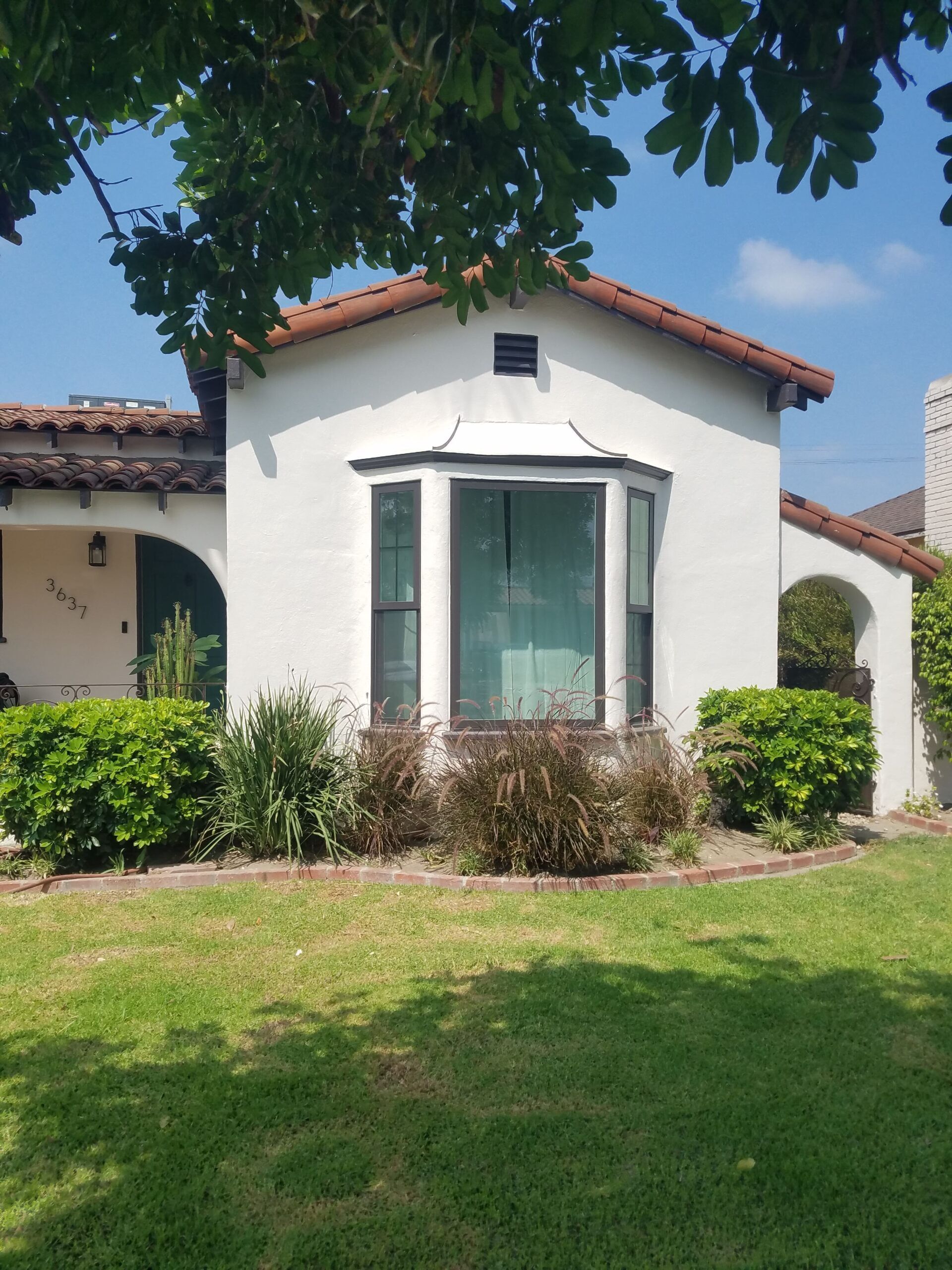 A white house with a large bay window in the front yard