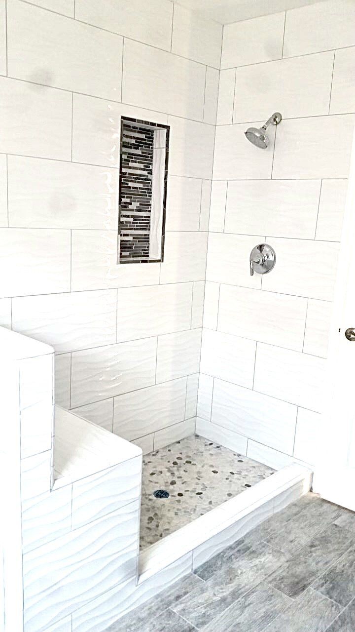 A bathroom with white tiles and a walk in shower.