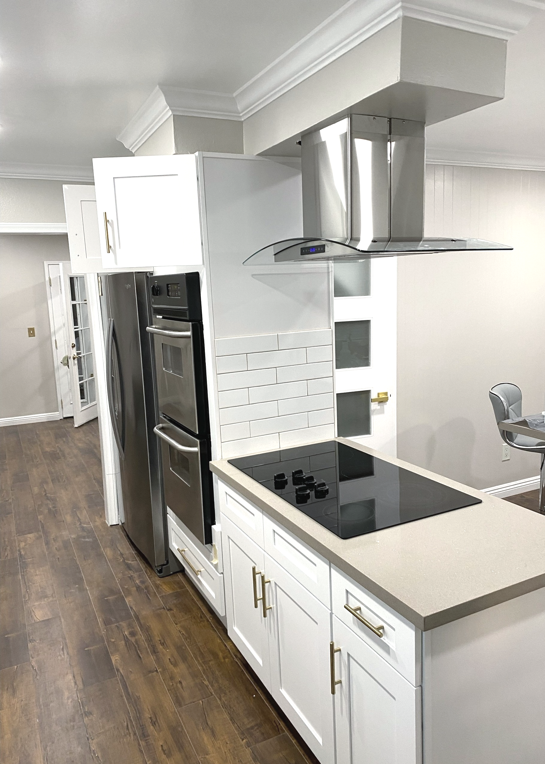A kitchen with white cabinets , stainless steel appliances , a stove top oven and a refrigerator.