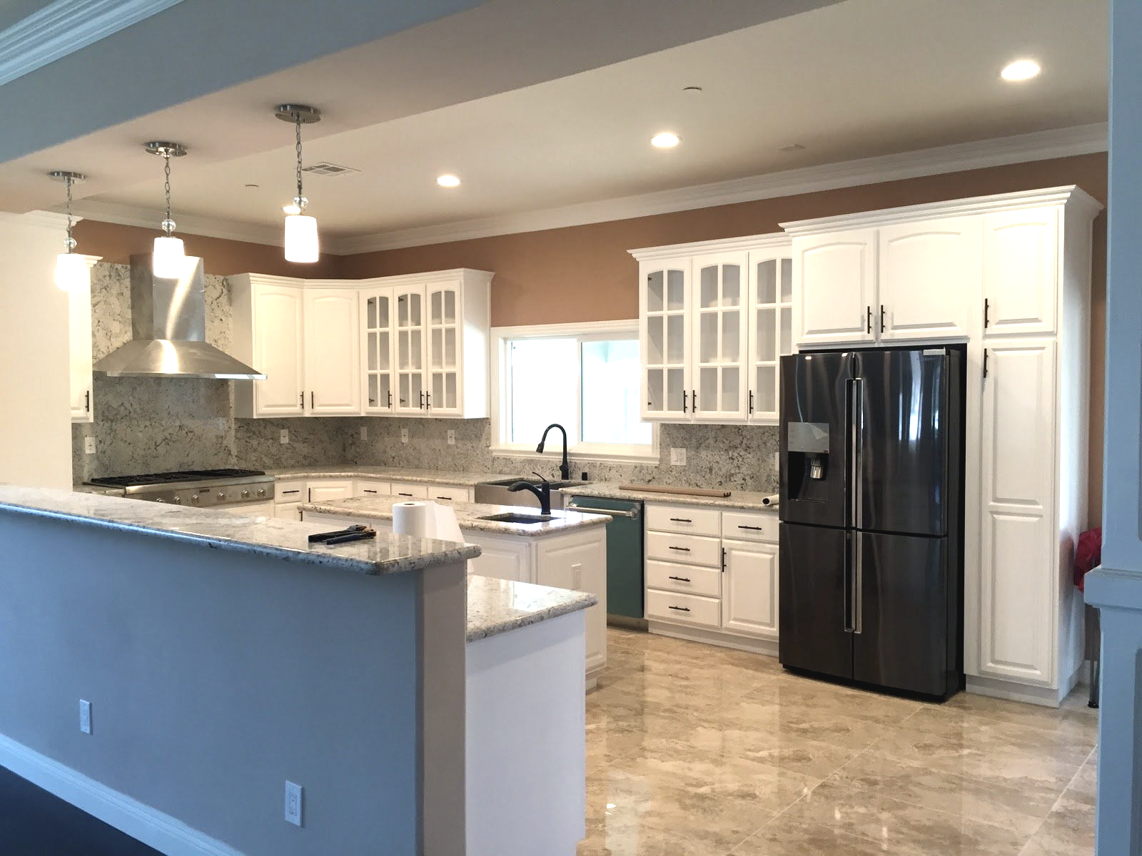 A kitchen with white cabinets and a black refrigerator