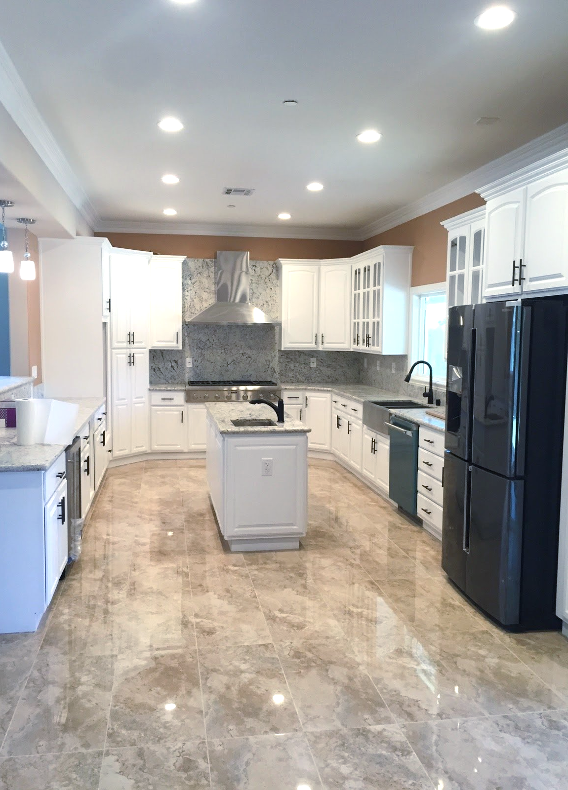 A large kitchen with white cabinets and a black refrigerator.