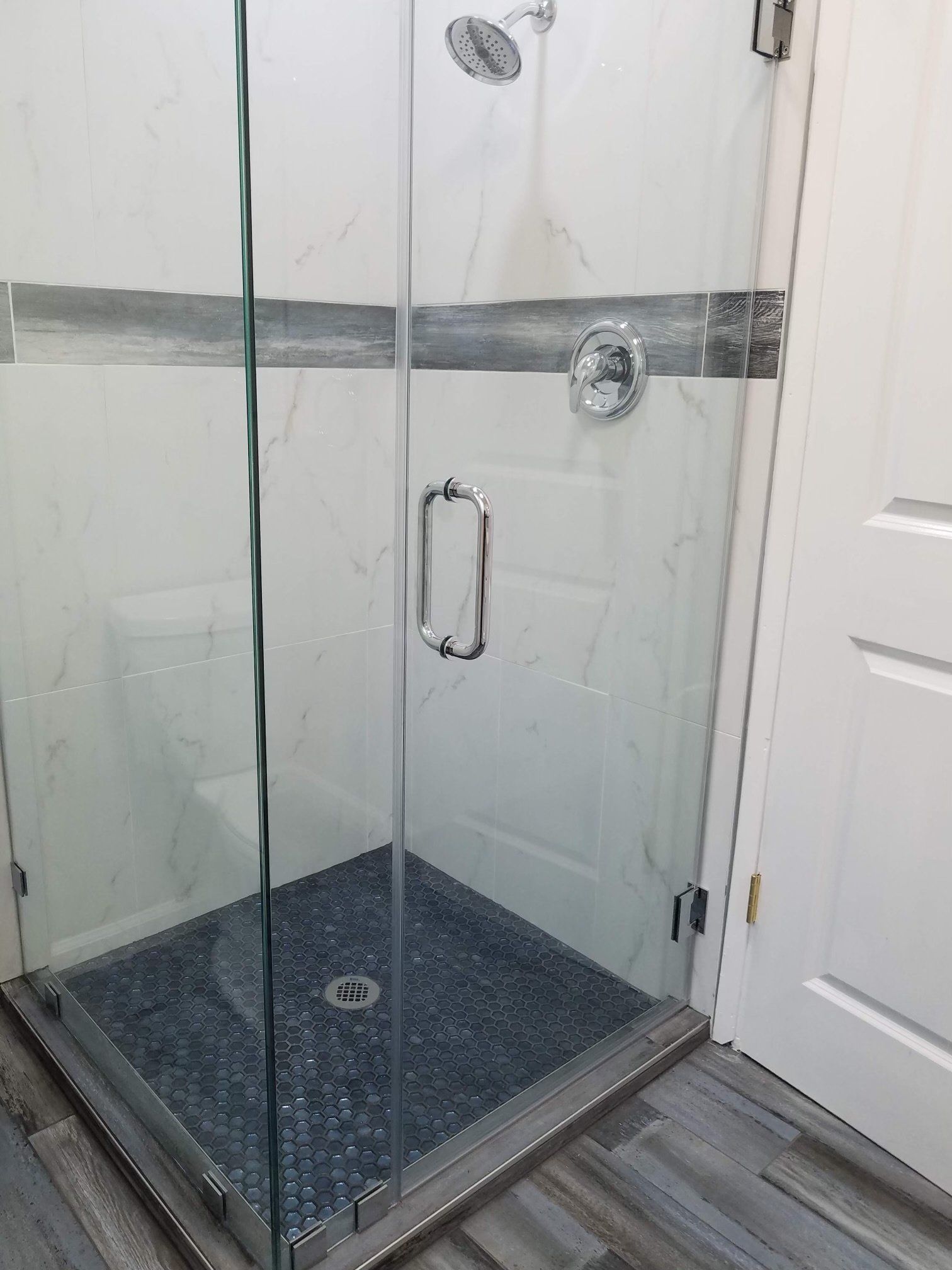 A bathroom with a walk in shower with a glass door.