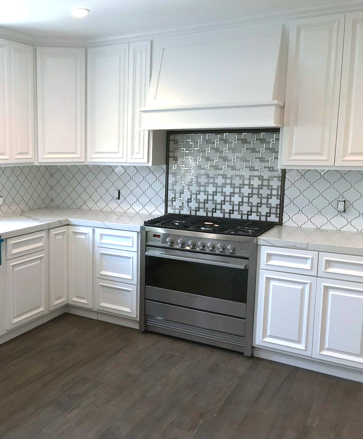 A kitchen with white cabinets and a stove top oven
