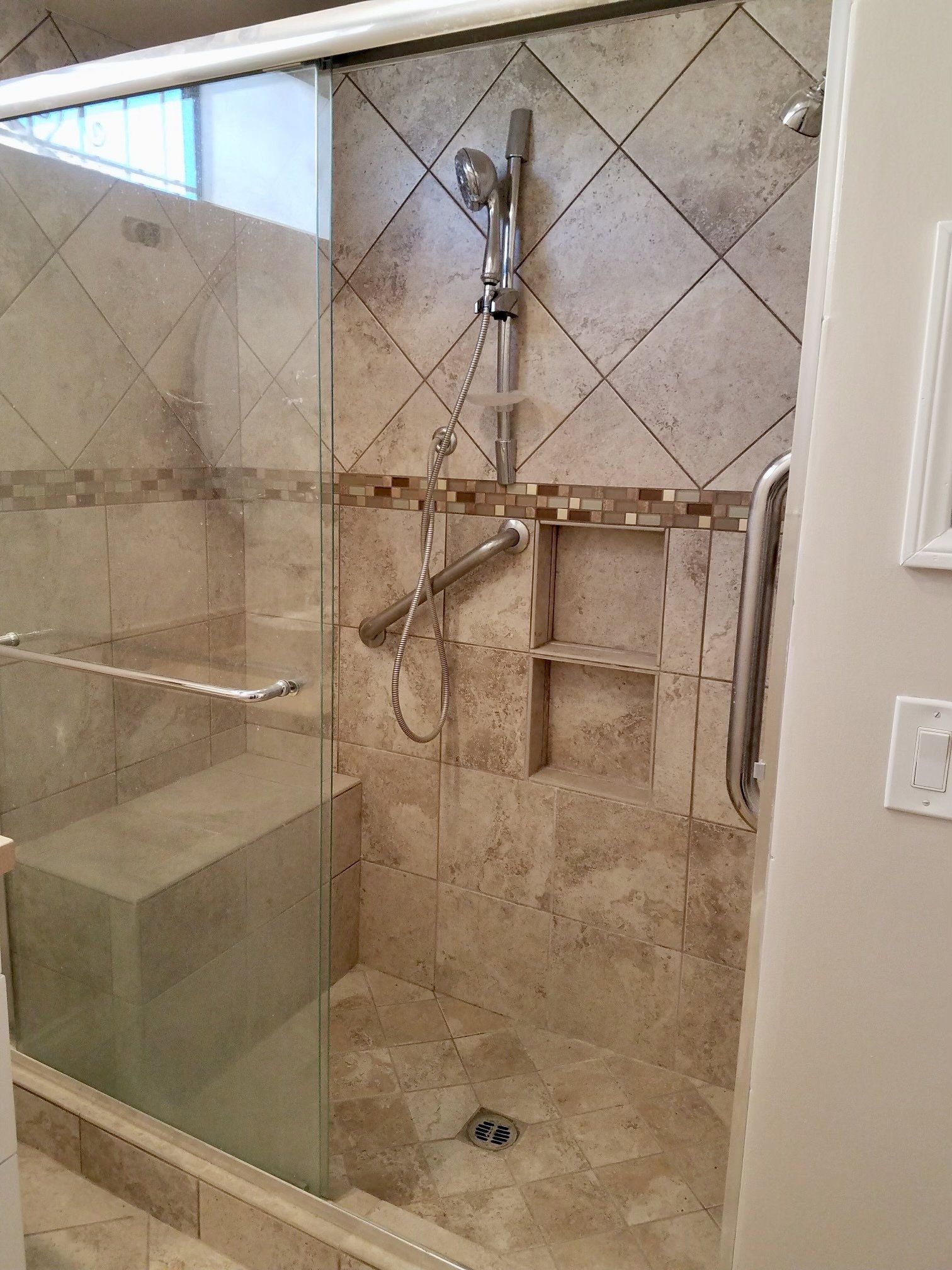 A bathroom with a walk in shower with a glass door.