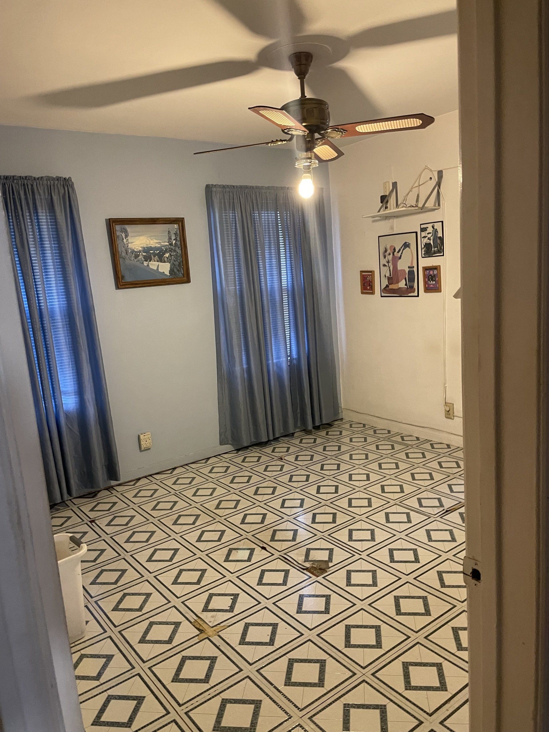A bedroom with a ceiling fan and a patterned floor.