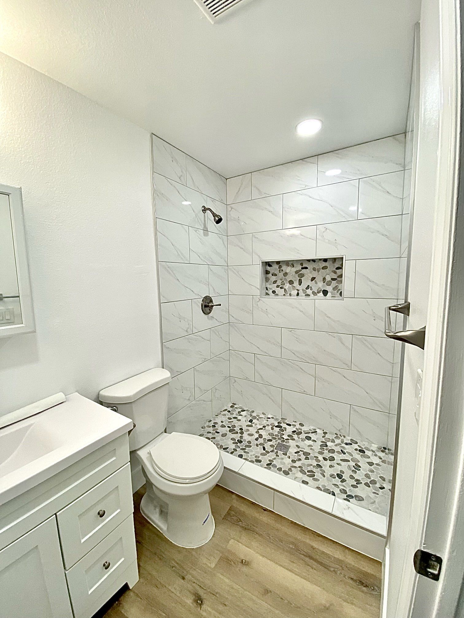 A bathroom with a toilet , sink and shower.