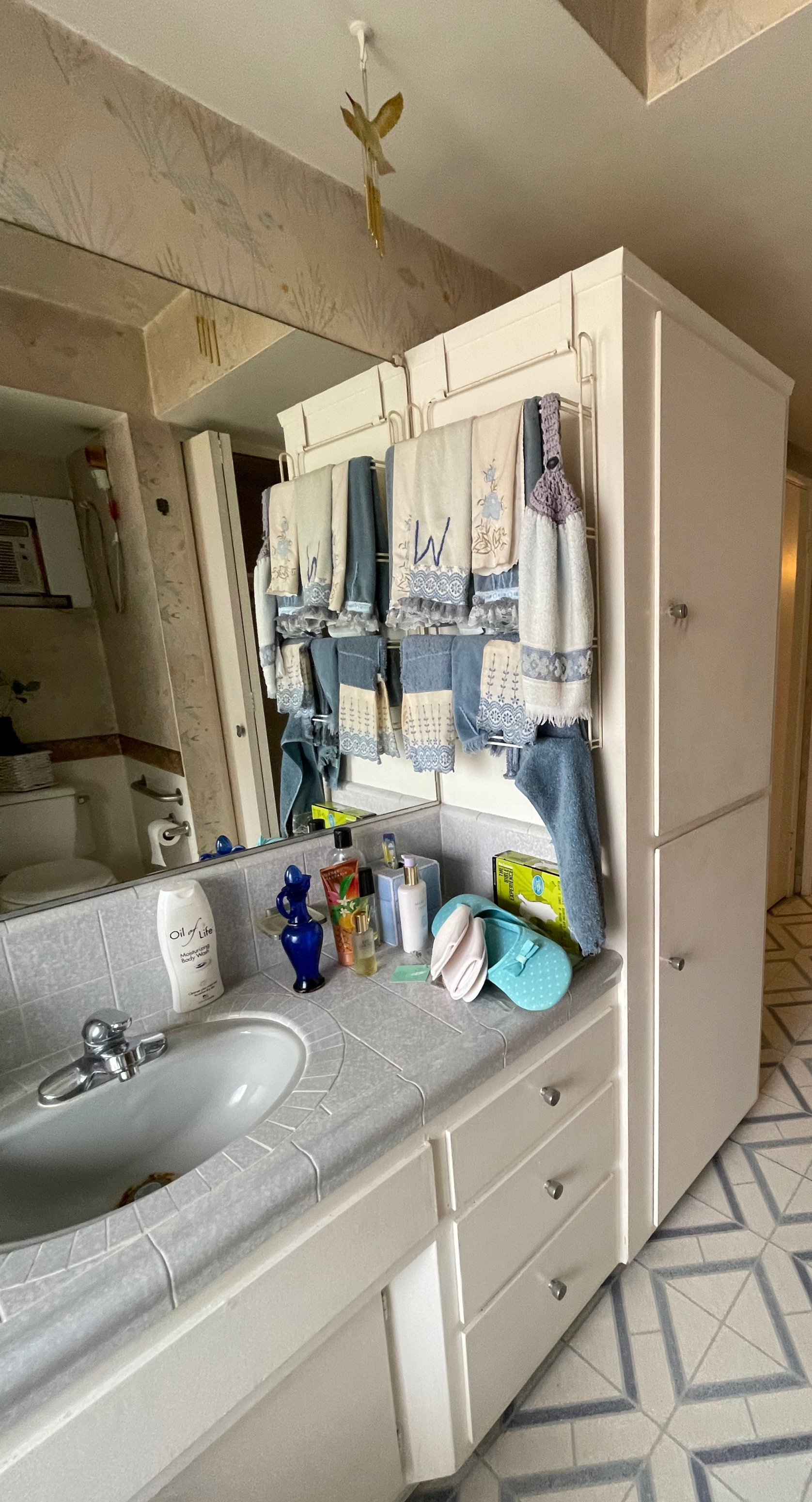 A bathroom with a sink , mirror and towels hanging on the wall.