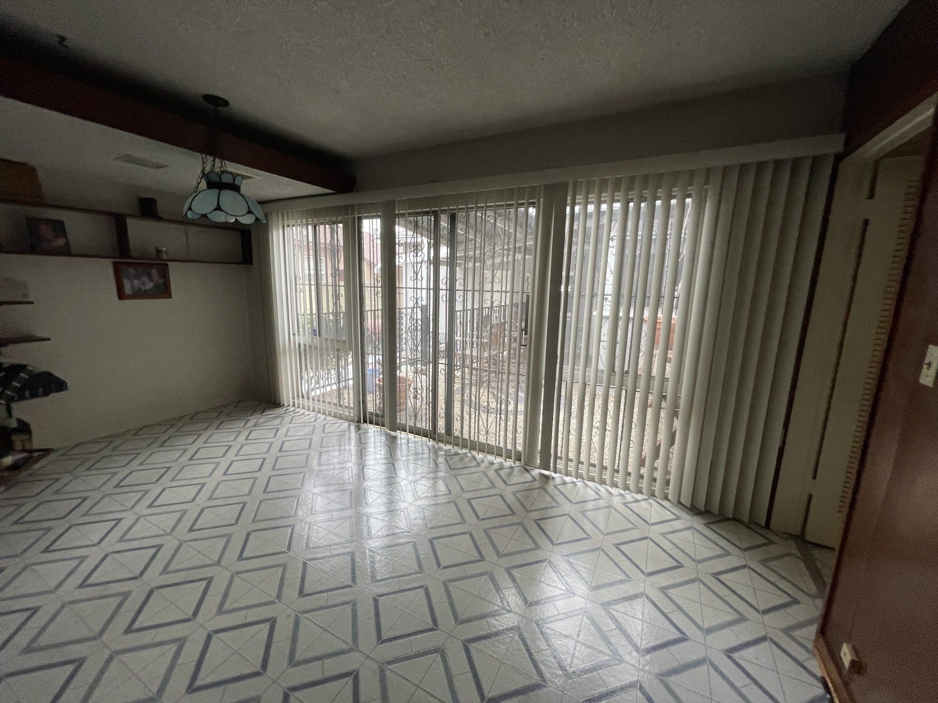 An empty living room with sliding glass doors and blinds.