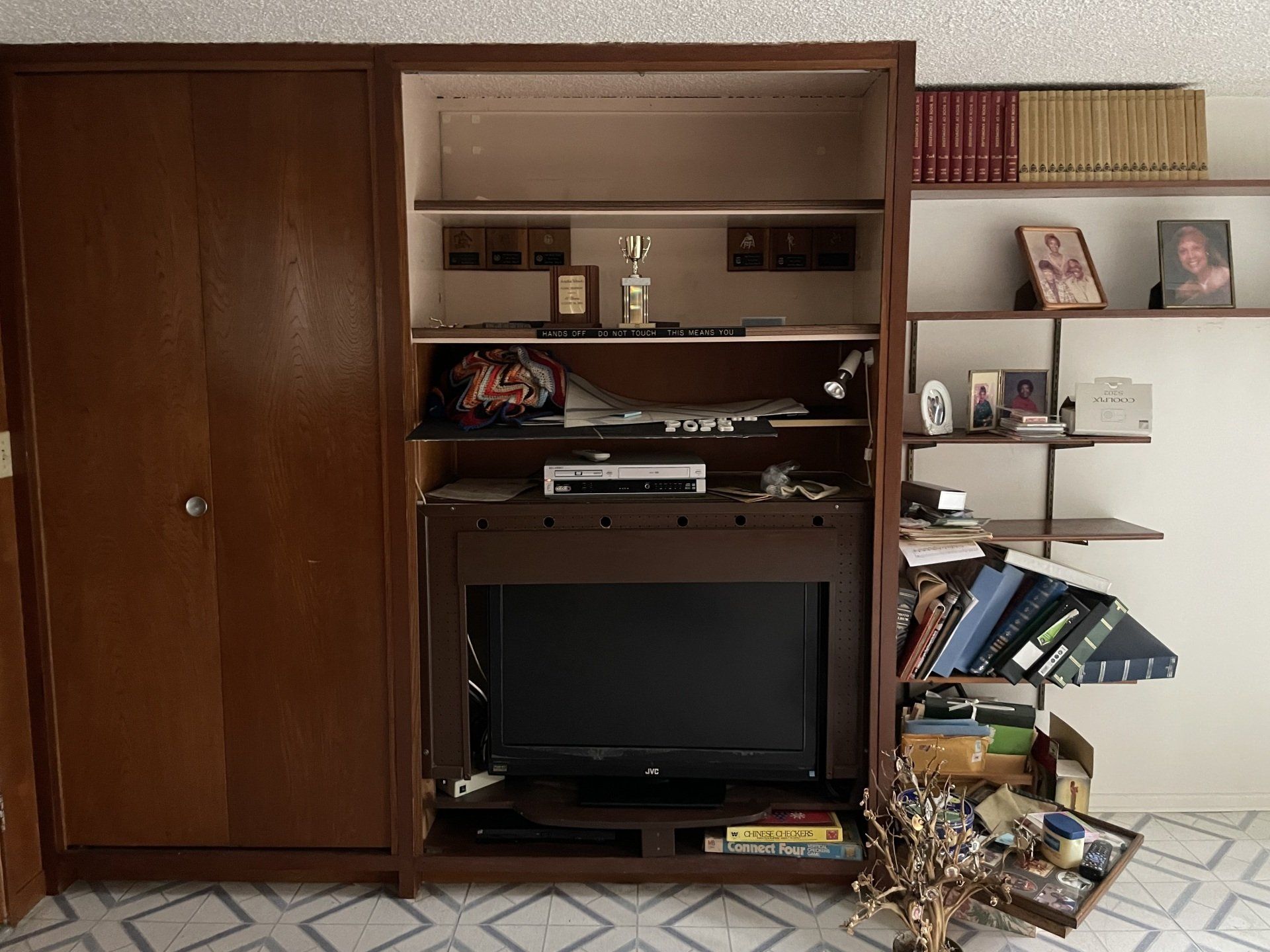A living room with a tv and a shelf with books on it