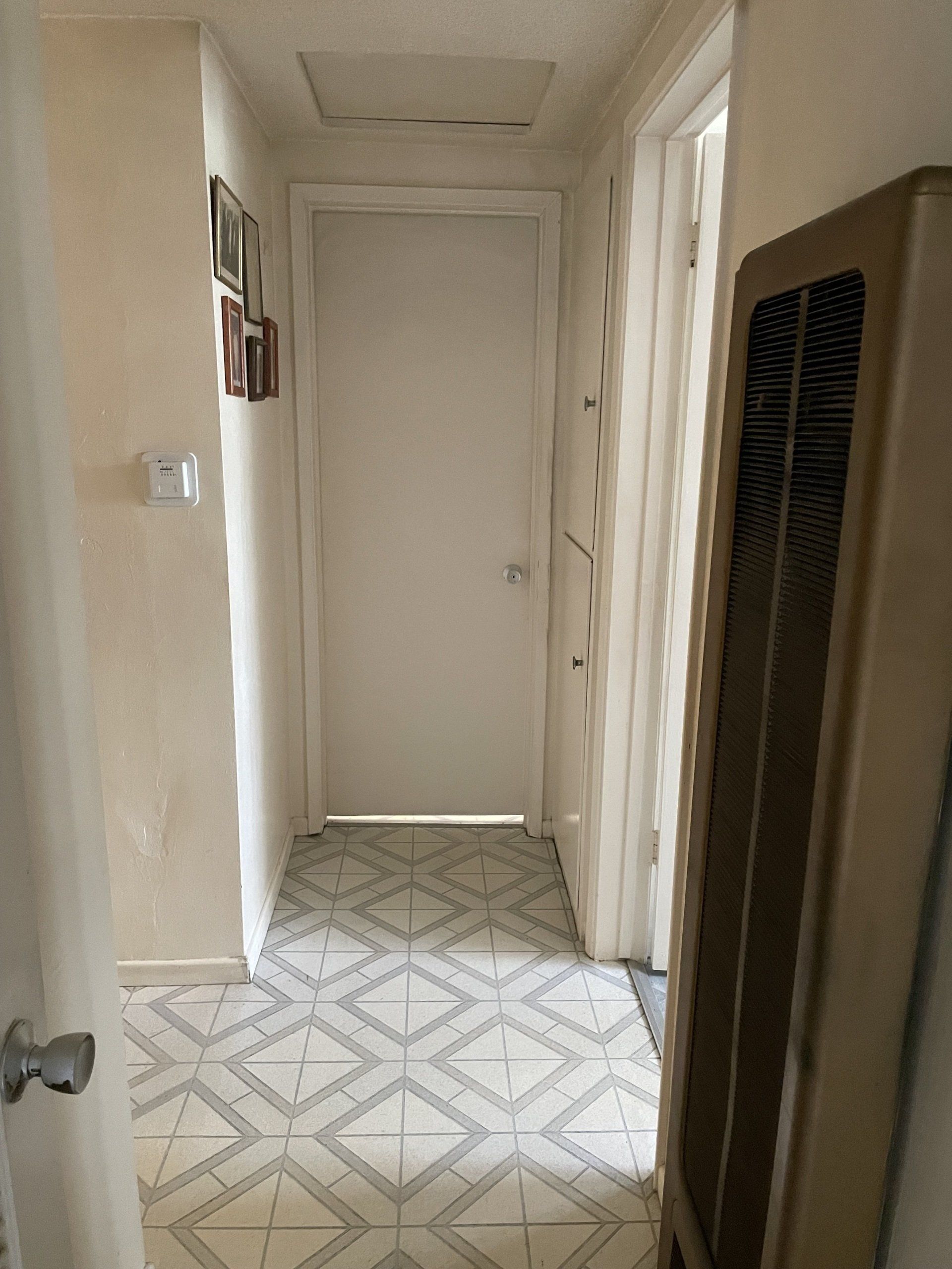 A hallway with a tiled floor and a white door