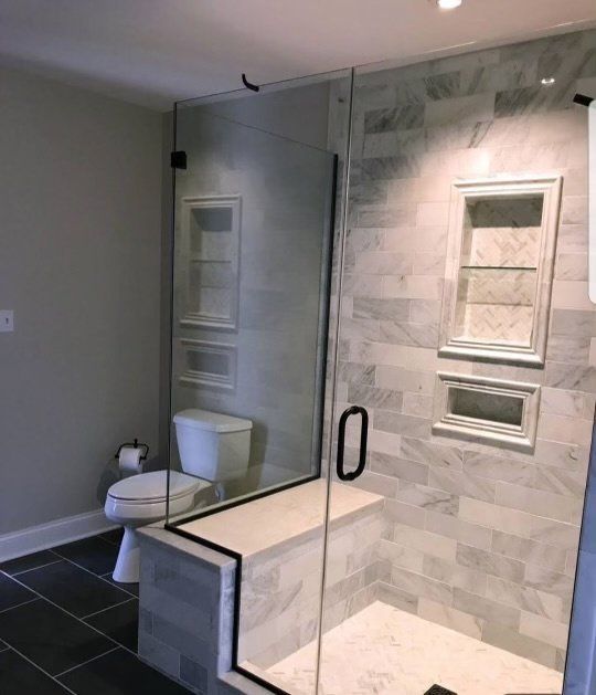 A bathroom with a toilet and a walk in shower with a glass door.