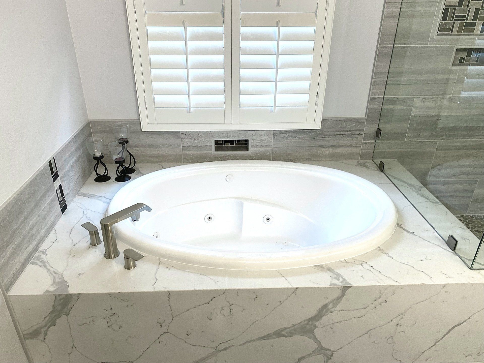 A bathtub in a bathroom with a window and shutters