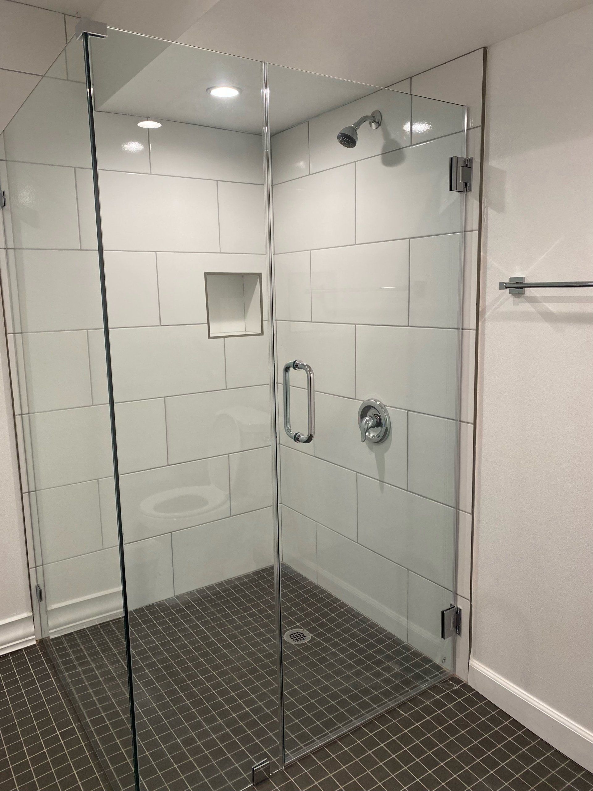 A bathroom with a walk in shower with a glass door