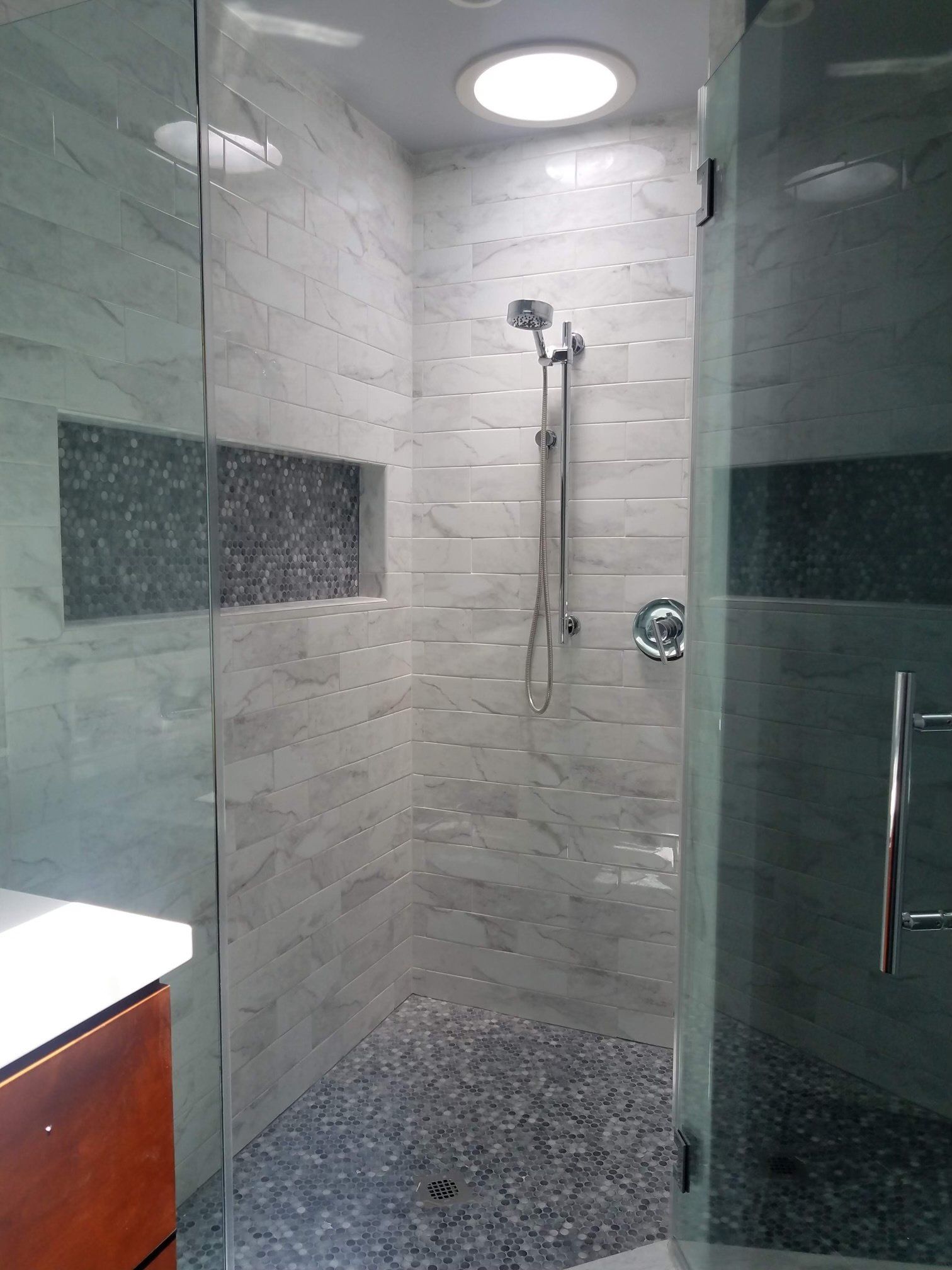 A bathroom with a walk in shower and a skylight.