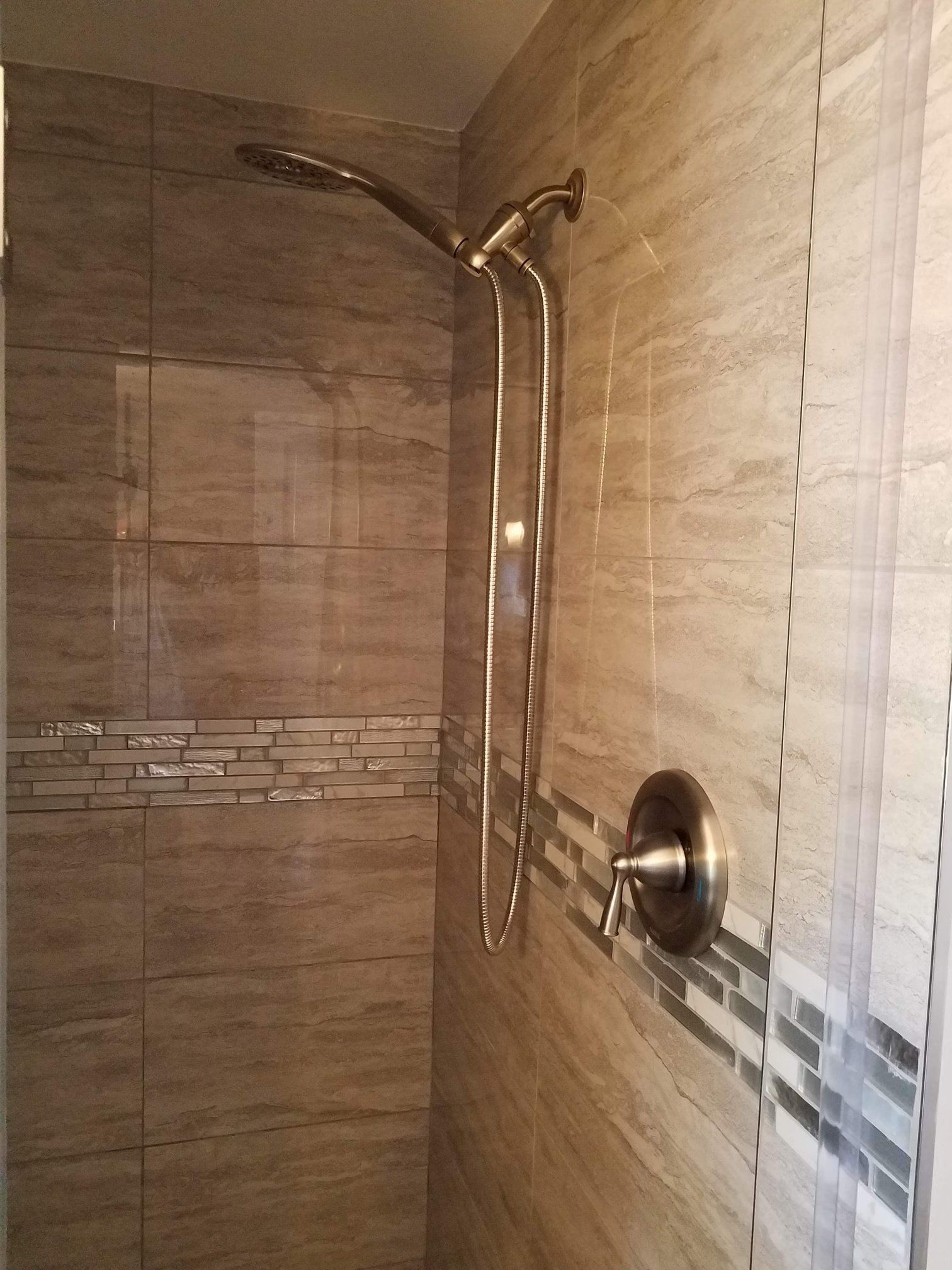 A shower with a stainless steel shower head on the wall.